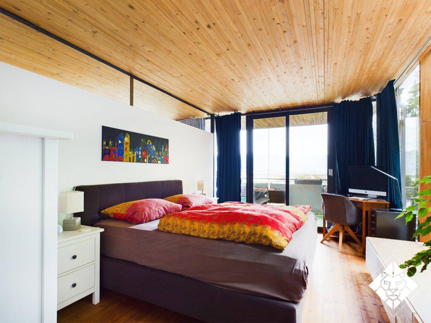 Gemütliches Schlafzimmer mit Holzboden, großem Bett und Zugang zu einem Balkon mit Aussicht.