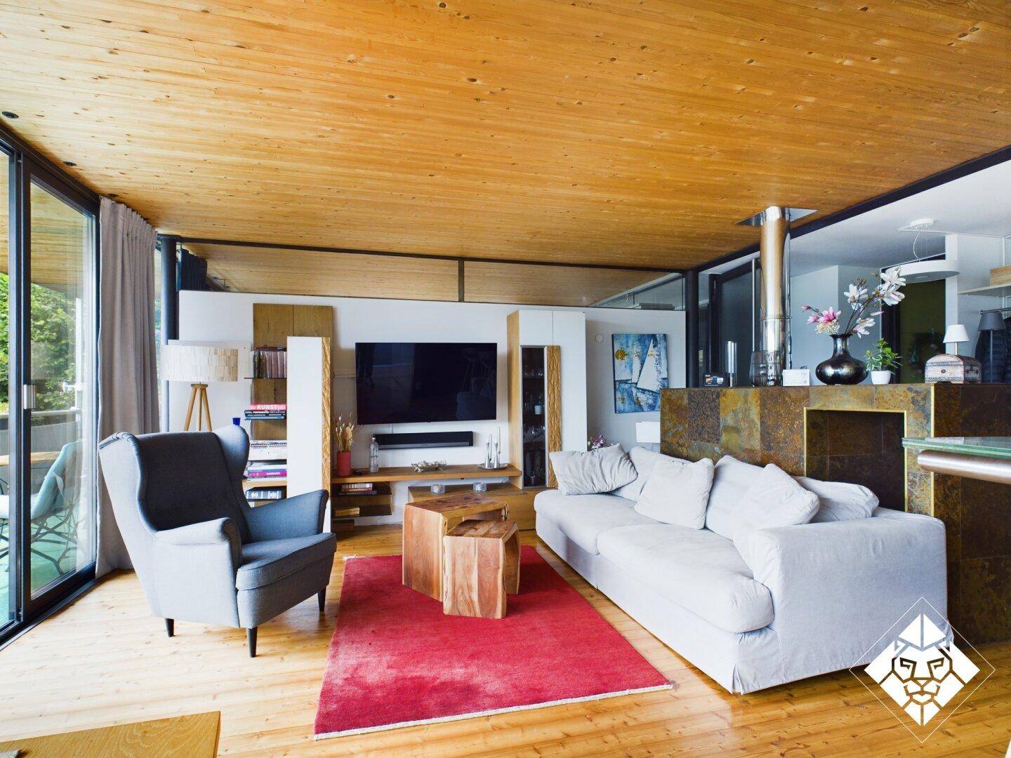 Heller, offener Wohn- und Essbereich mit Holzboden, Holzdecke und großen Fensterfronten.