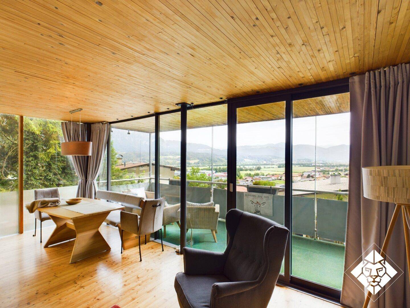 Heller Wohn- und Essbereich mit Holzboden, Panoramablick und Zugang zum Balkon.