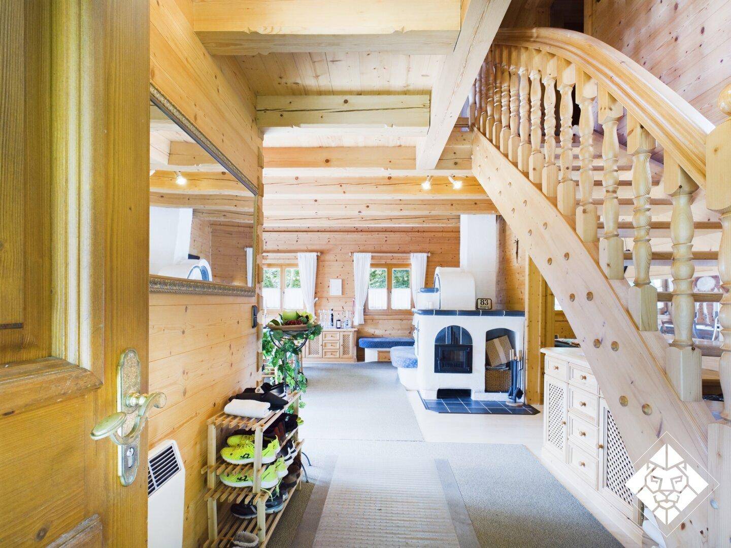 Gemütlicher Eingangsbereich mit Holzvertäfelung, rustikaler Treppe und traditionellem Kachelofen.