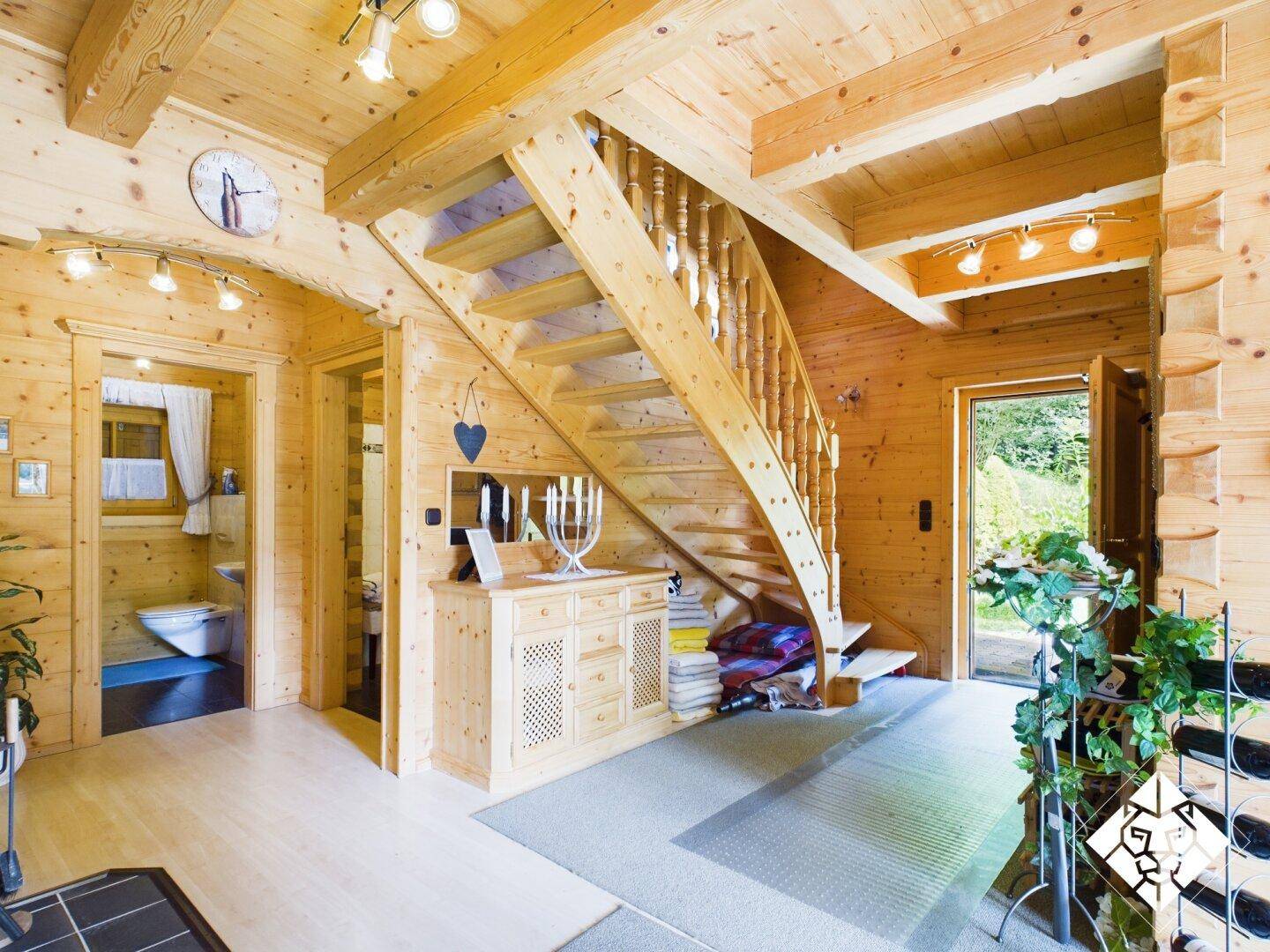 Heller Flur mit Holzvertäfelung, geschwungener Holztreppe und Zugang zu einem Gäste-WC.