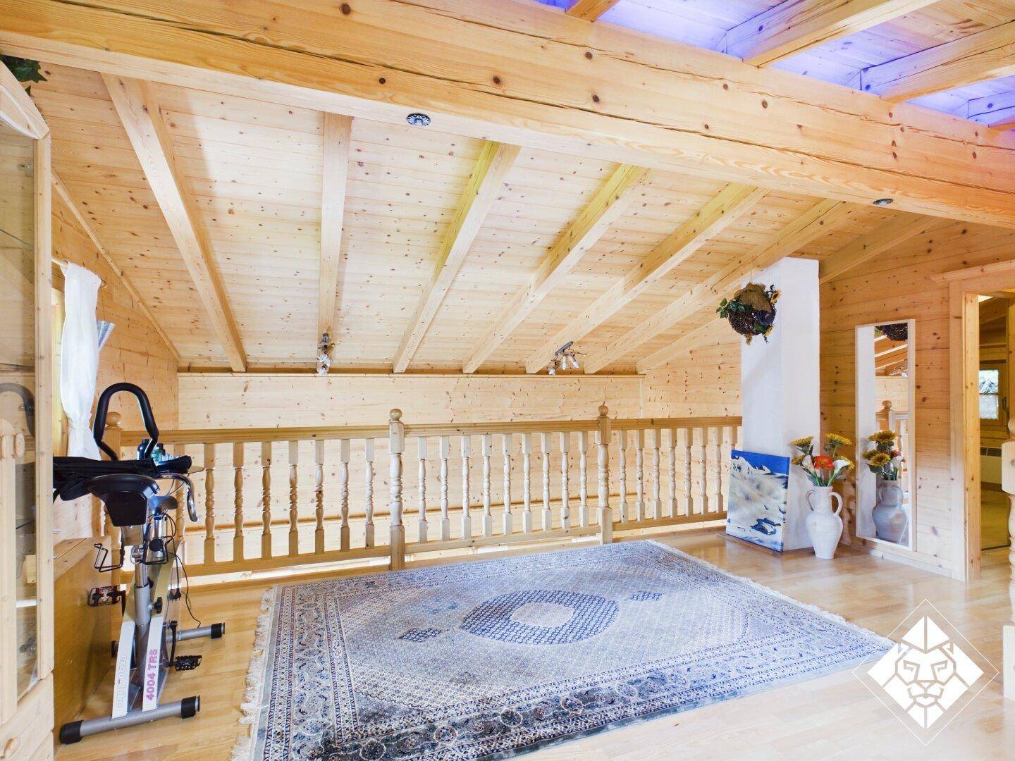Helle Galerie im Obergeschoss mit Holzboden, Teppich und einem Fitnessgerät.