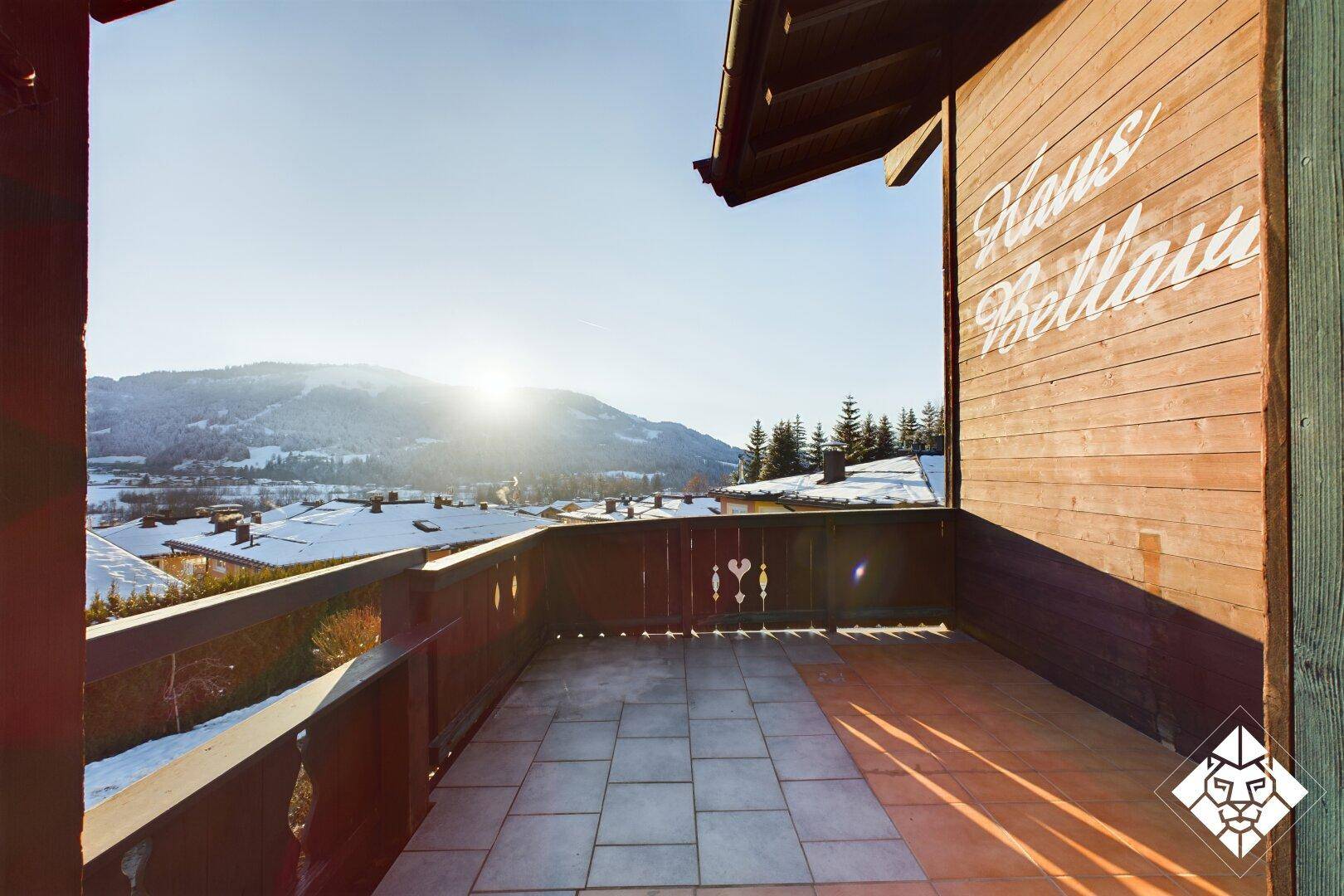 Sonniger Balkon mit Fliesenboden und weitem Blick auf die verschneite Berglandschaft.