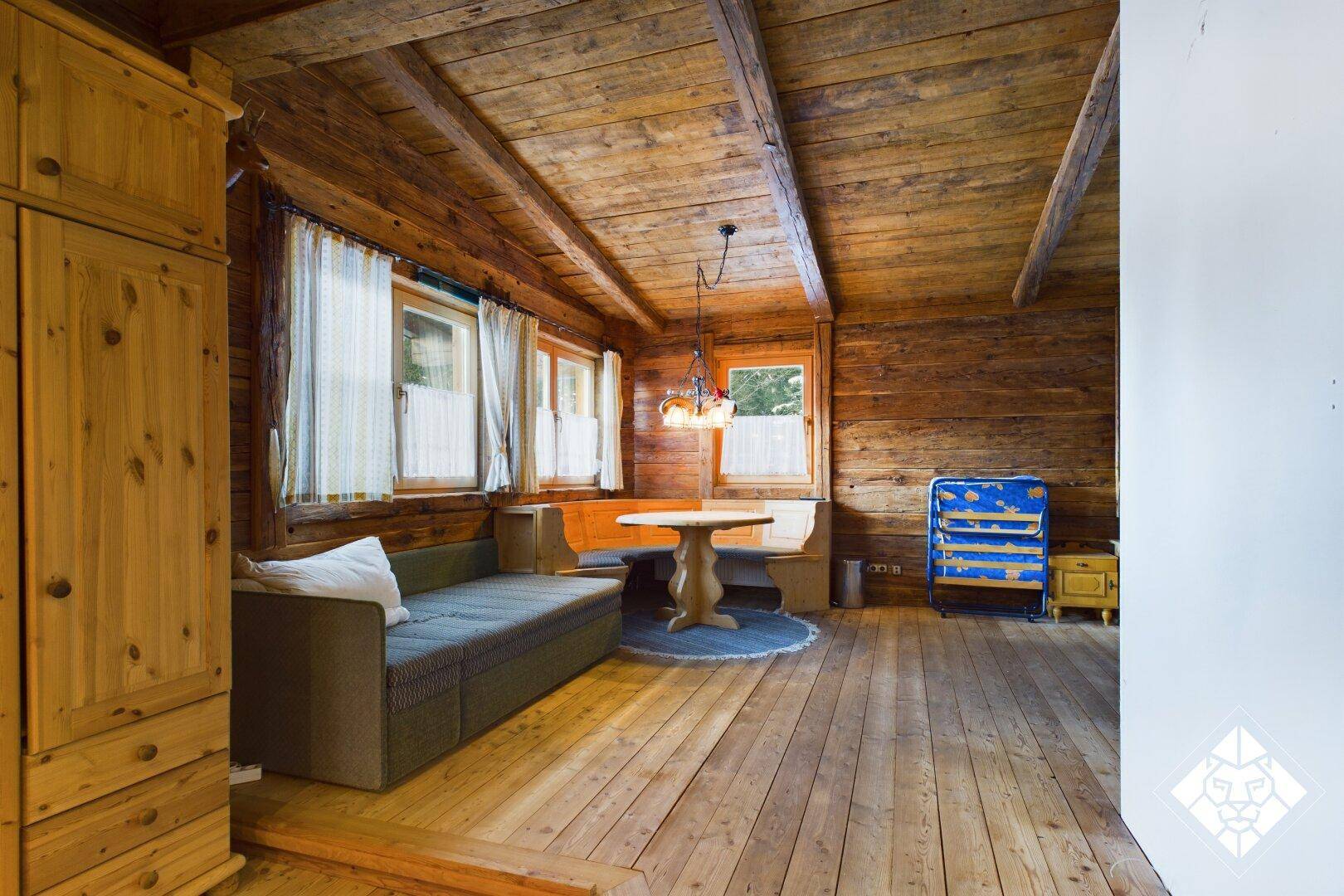 Rustikaler Wohn- und Essbereich mit Holzwänden, Holzbalkendecke und gemütlicher Sitzecke.