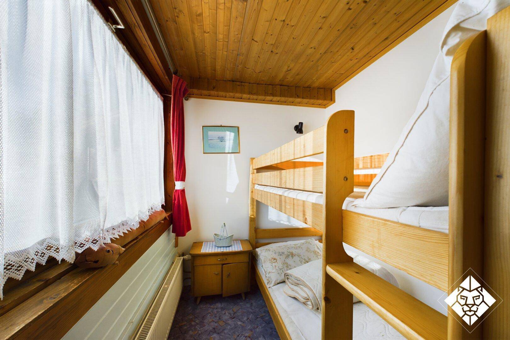 Kleines Schlafzimmer mit Etagenbetten, Holzverkleidung und Teppichboden.