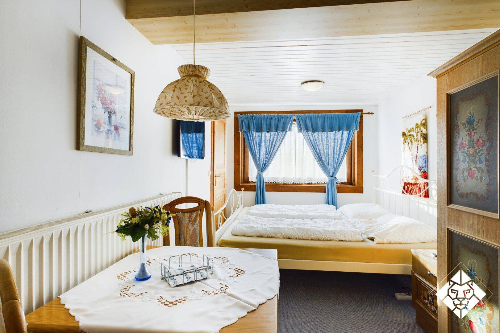 Gemütliches Schlafzimmer mit Doppelbett, kleinem Esstisch und traditioneller Einrichtung.