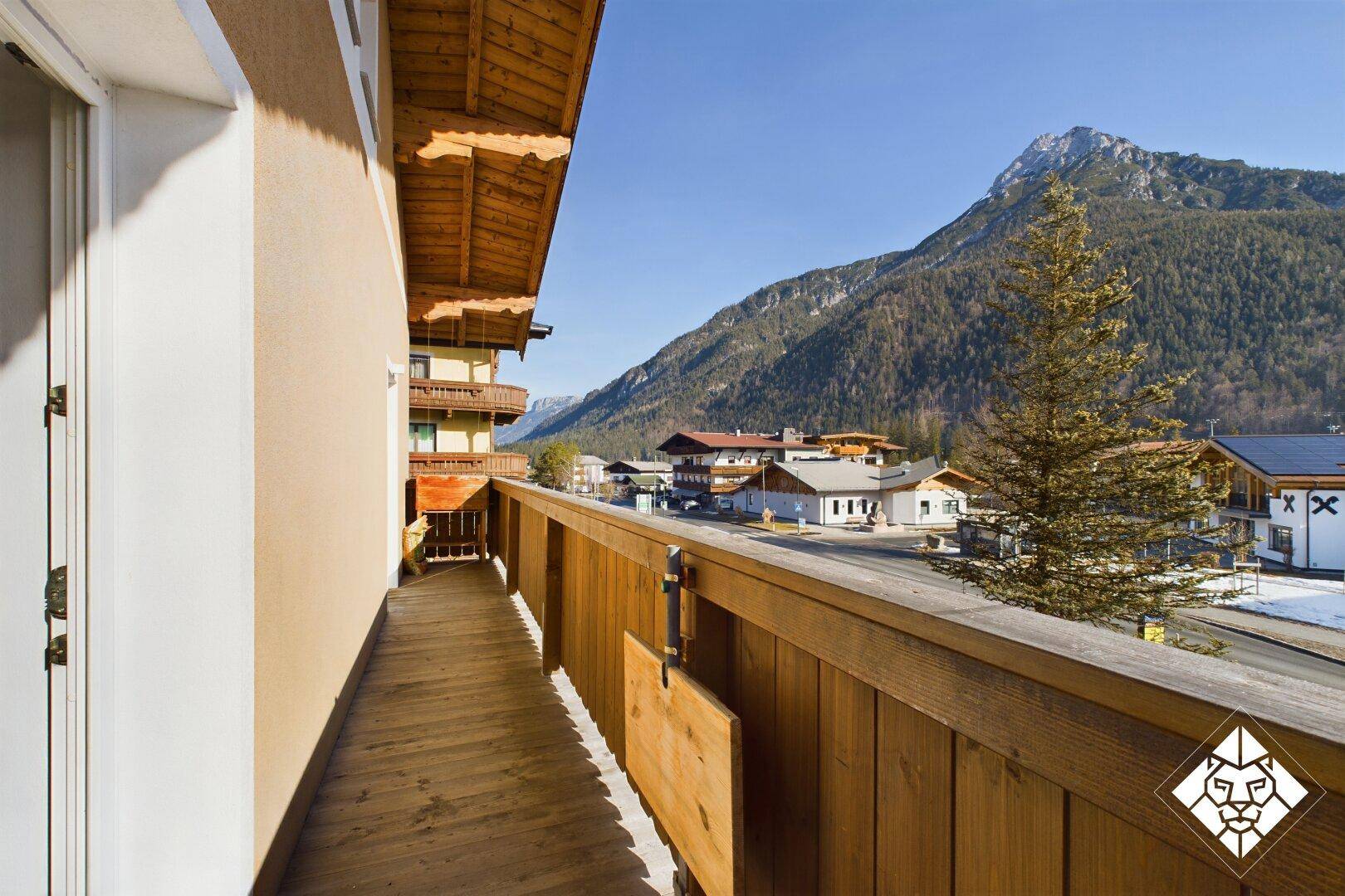 Geräumiger Holzbalkon mit weitem Blick auf die umliegenden Berge und das Tal.