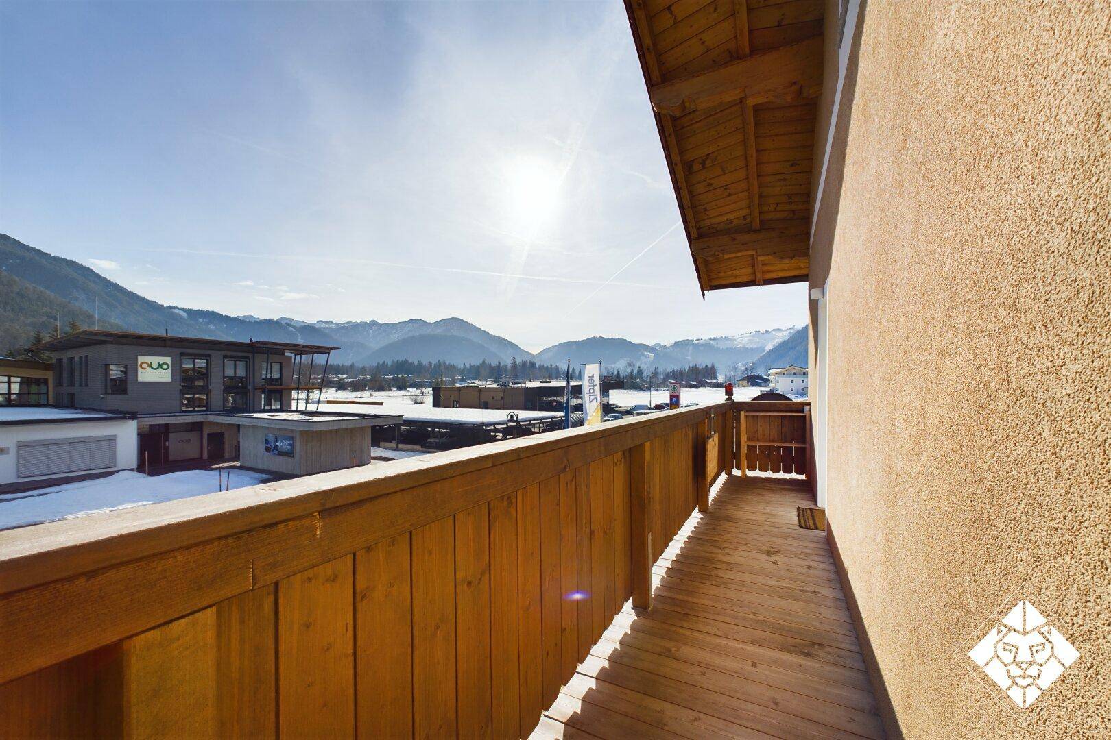 Langer Holzbalkon mit Bergblick und Sonnenschein, ideal zum Entspannen.