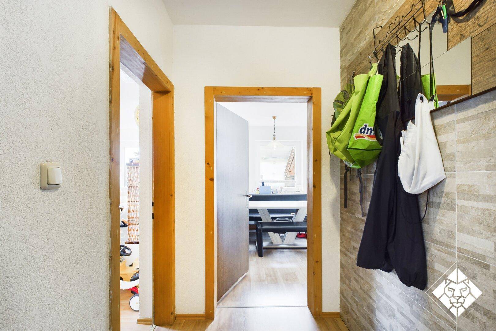 Eingangsbereich mit Garderobe, Fliesenwand und Zugang zu weiteren Räumen.