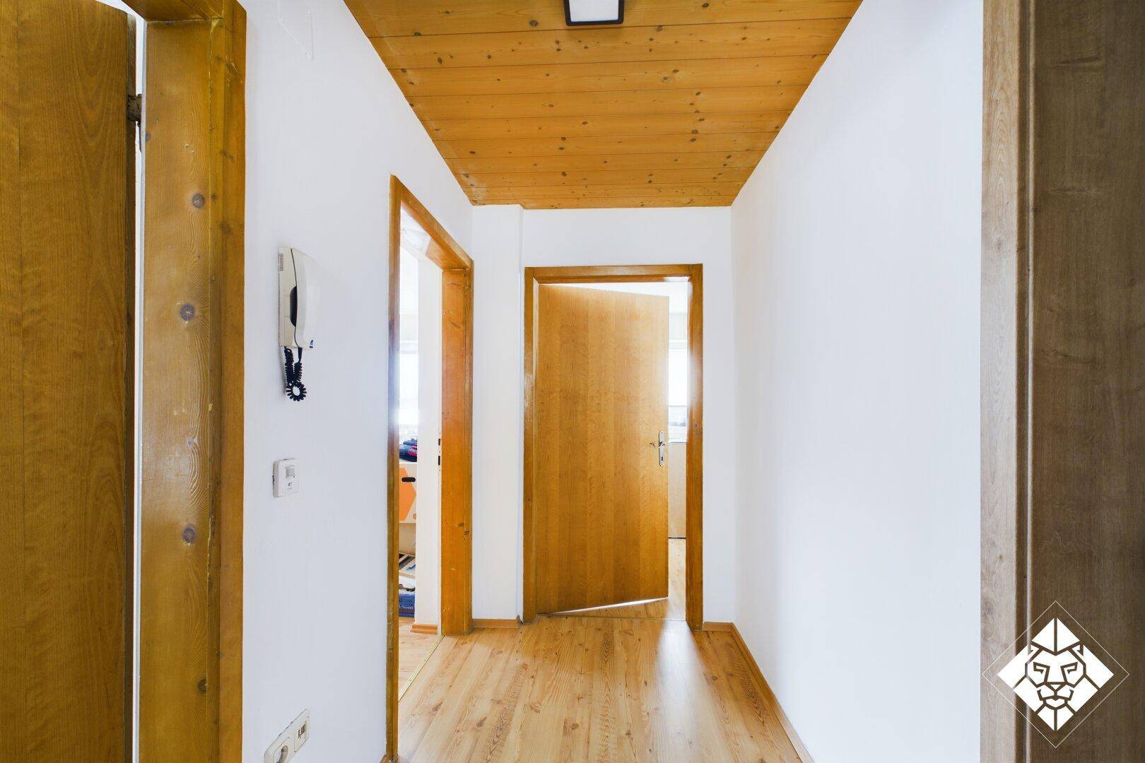 Heller Flur mit Holzboden und Holzdecke, der zu weiteren Räumen führt.