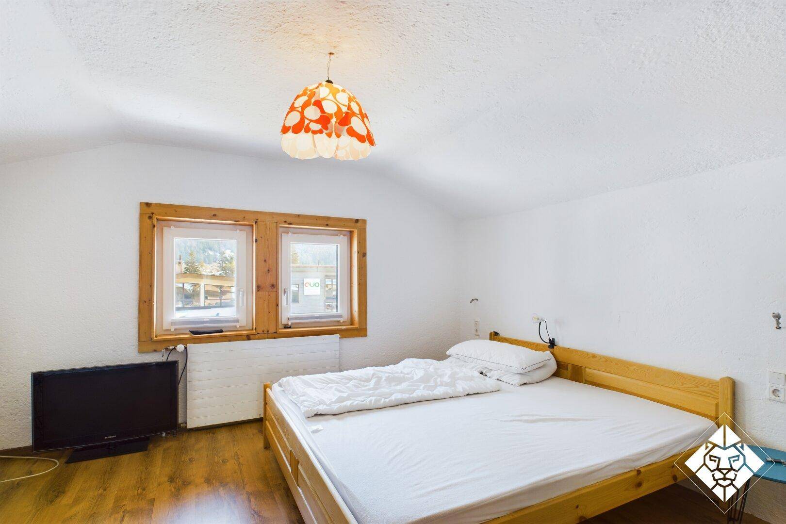 Schlafzimmer mit Holzboden, Doppelbett und Fenster mit Blick auf die Umgebung.