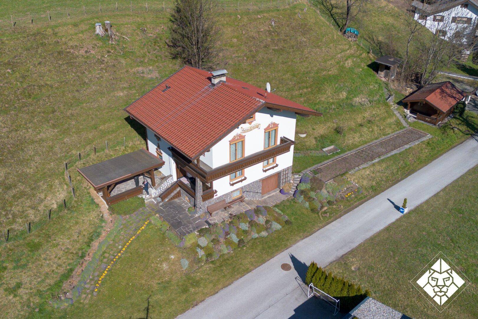 Haus im alpinen Stil mit rotem Ziegeldach und gepflegtem Vorgarten.