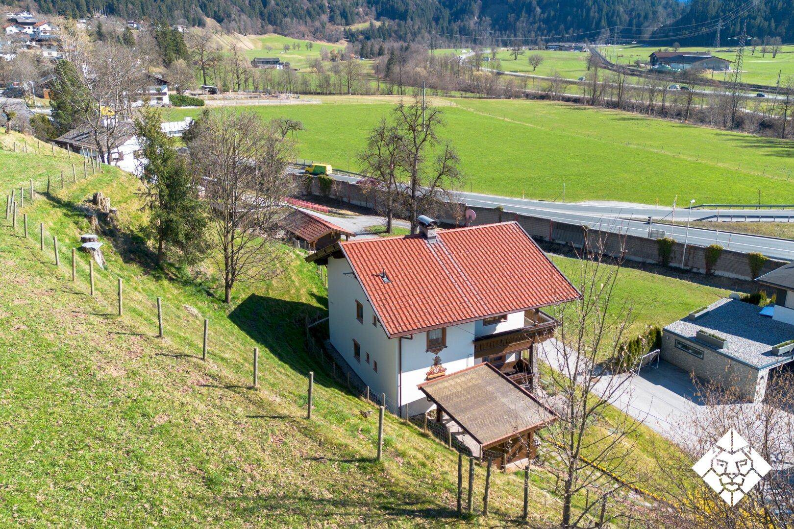 Luftaufnahme des Hauses in Hanglage mit Blick auf die umliegende Natur und Straße.