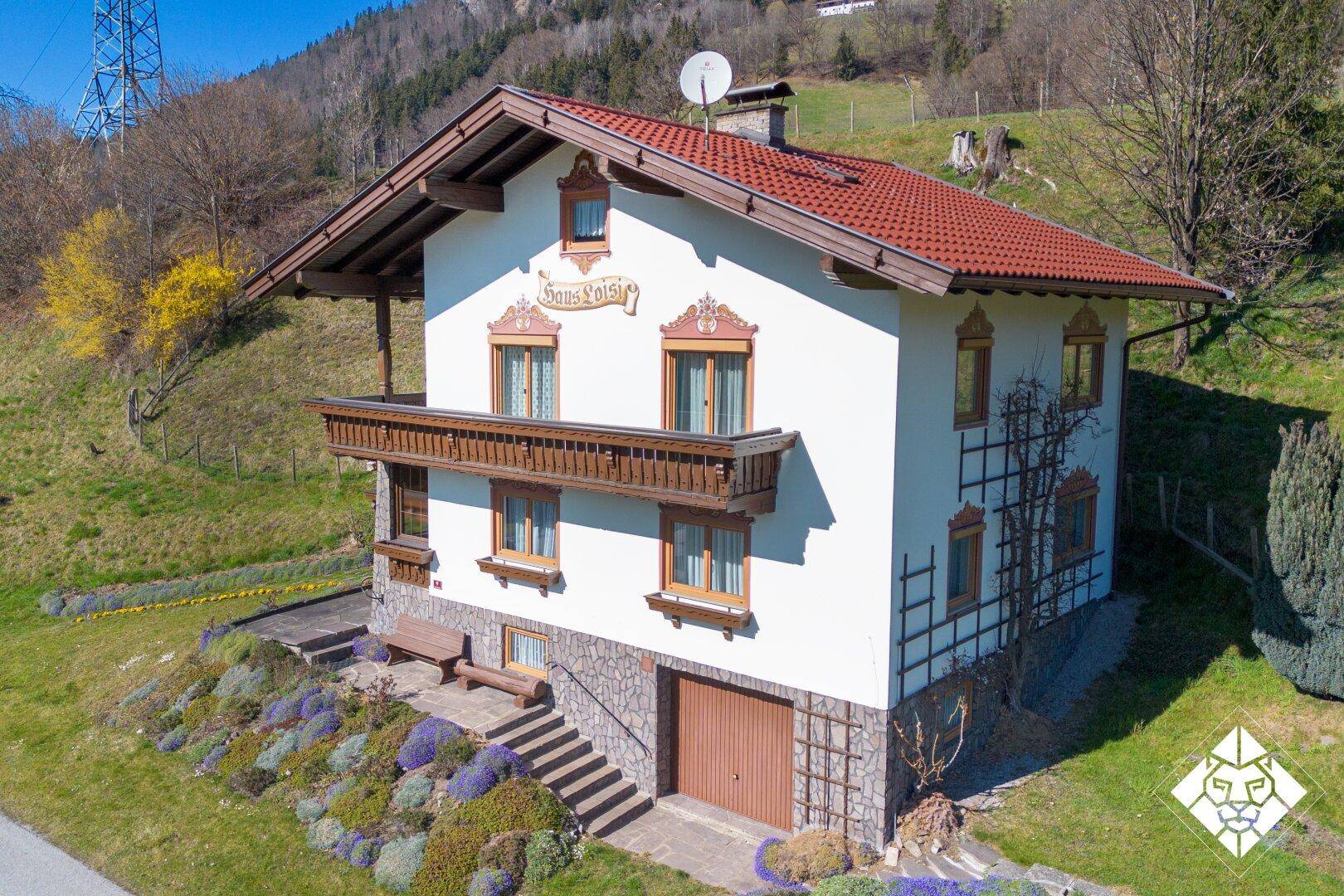Traditionelles Haus im alpinen Stil mit Holzbalkon und bemalter Fassade.