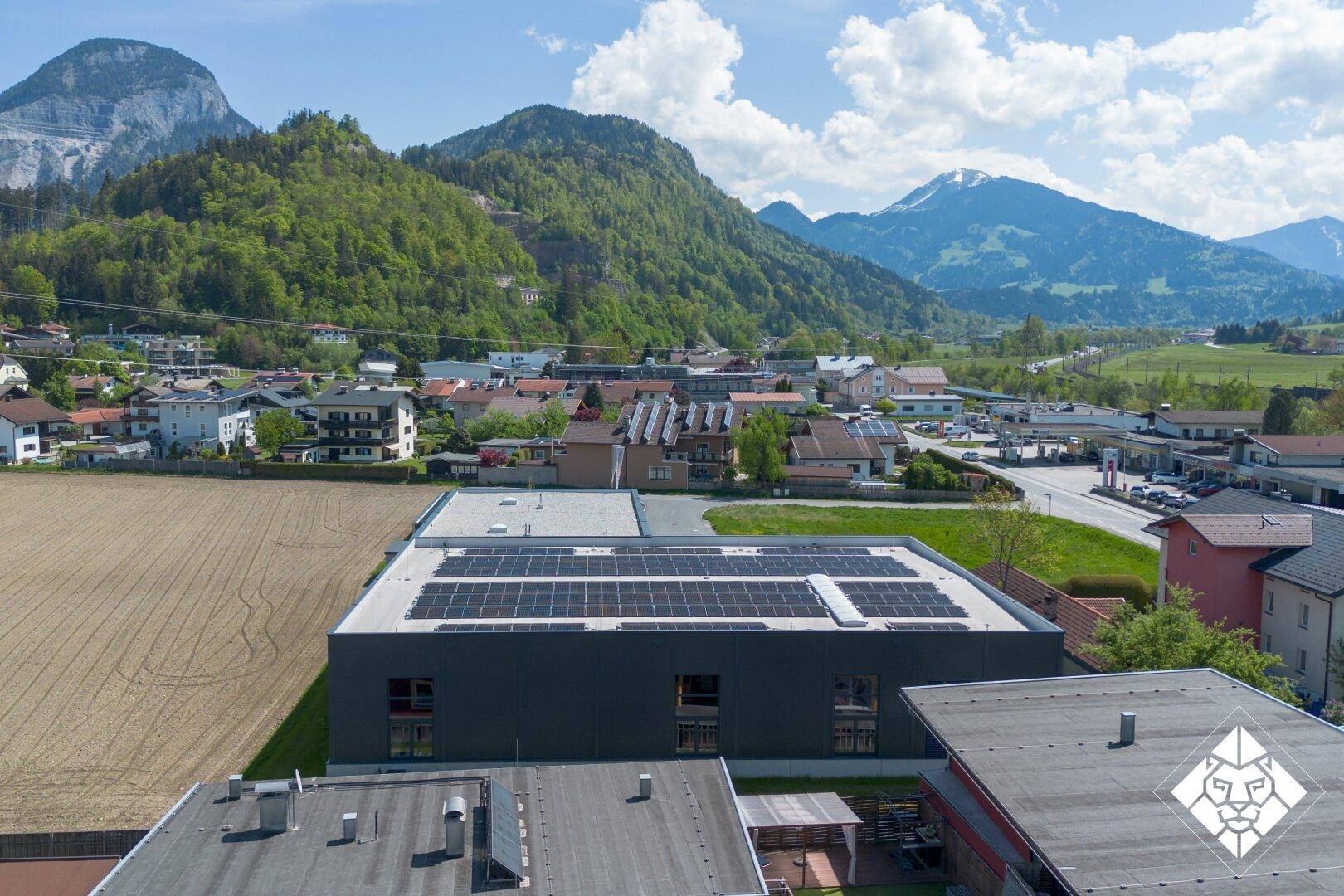 Dachansicht eines Gewerbegebäudes mit Photovoltaikanlage, eingebettet in eine malerische Berglandschaft.