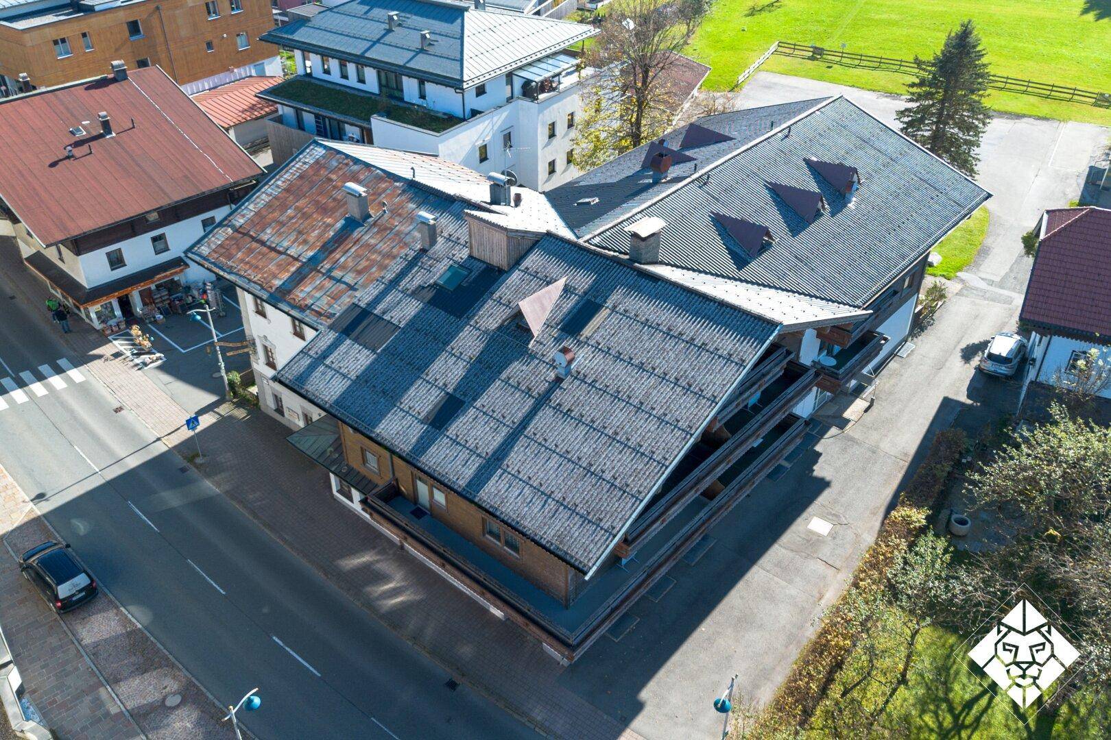 Dachansicht eines traditionellen Gebäudes mit mehreren Dächern und Balkonen an einer Straße.