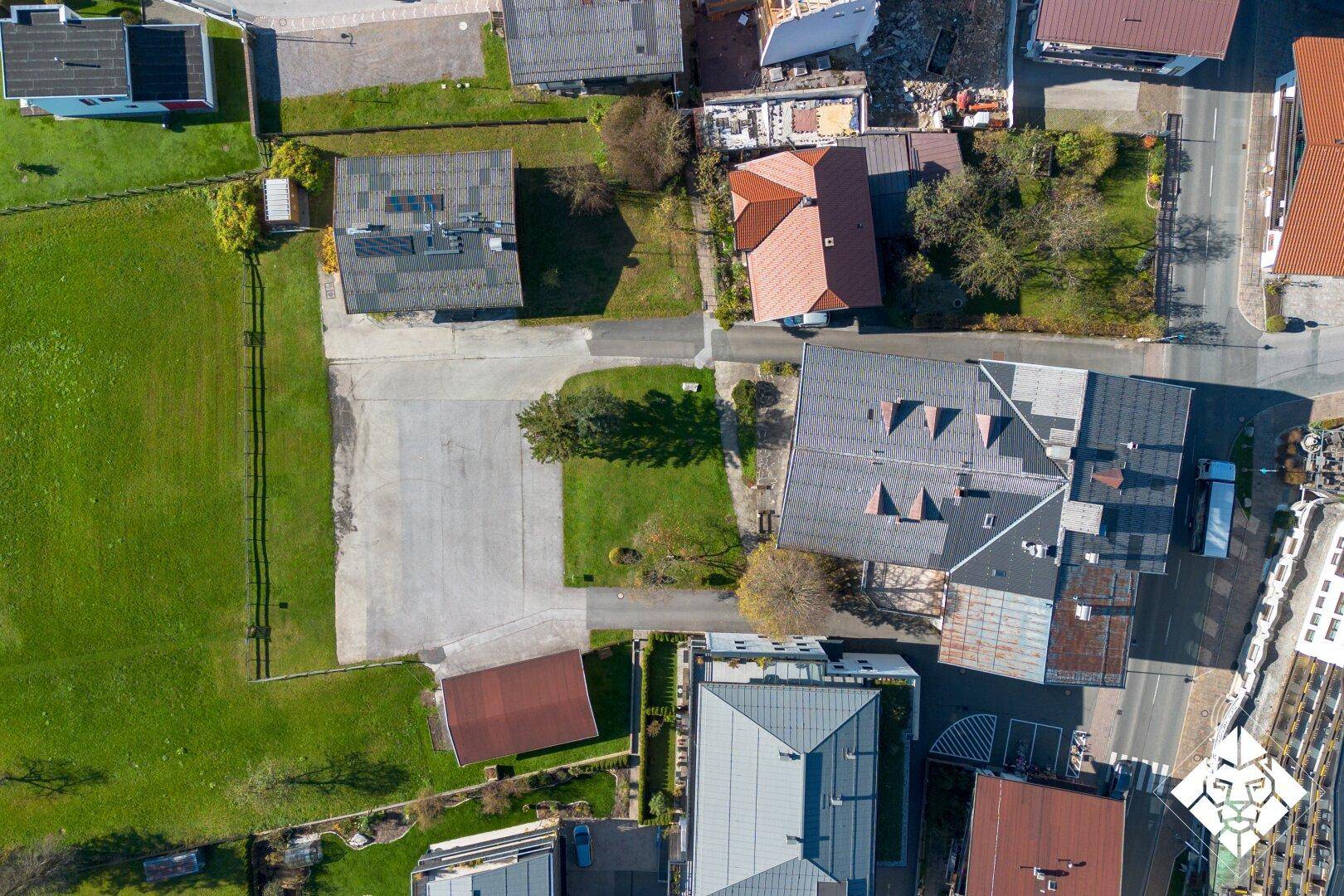 Senkrechte Luftaufnahme von Gebäuden, Straßen und Grünflächen in einer ländlichen Umgebung.
