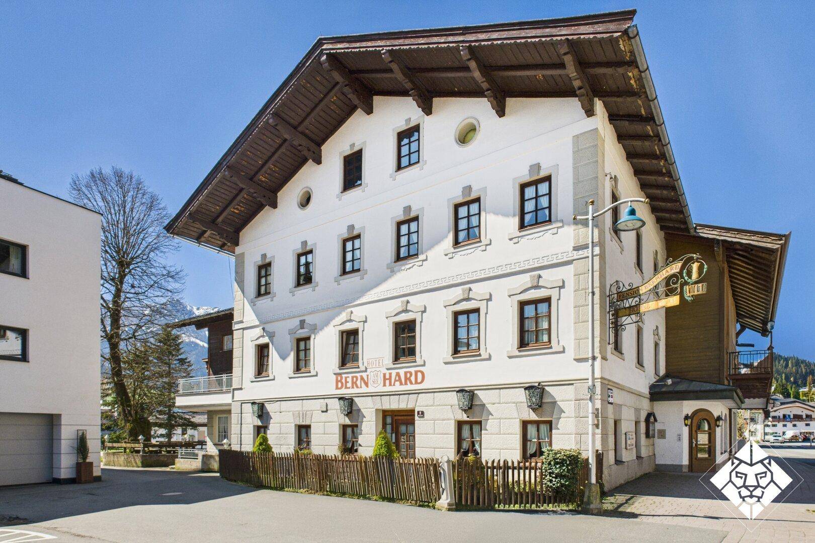 Traditionelles alpines Gebäude mit weißer Fassade und Holzelementen unter blauem Himmel.