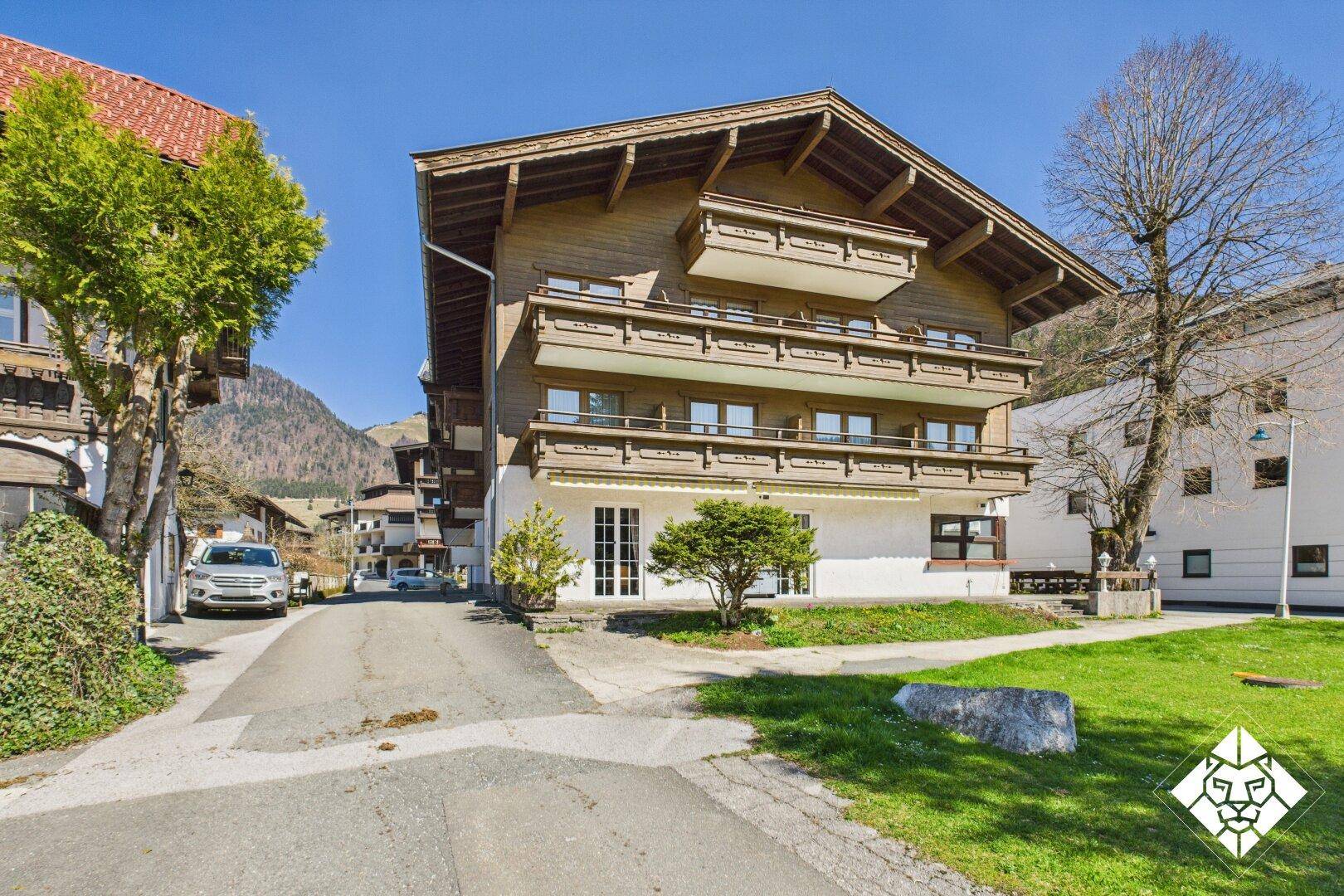 Traditionelles Holzgebäude mit mehreren Balkonen und alpiner Architektur in sonniger Umgebung.