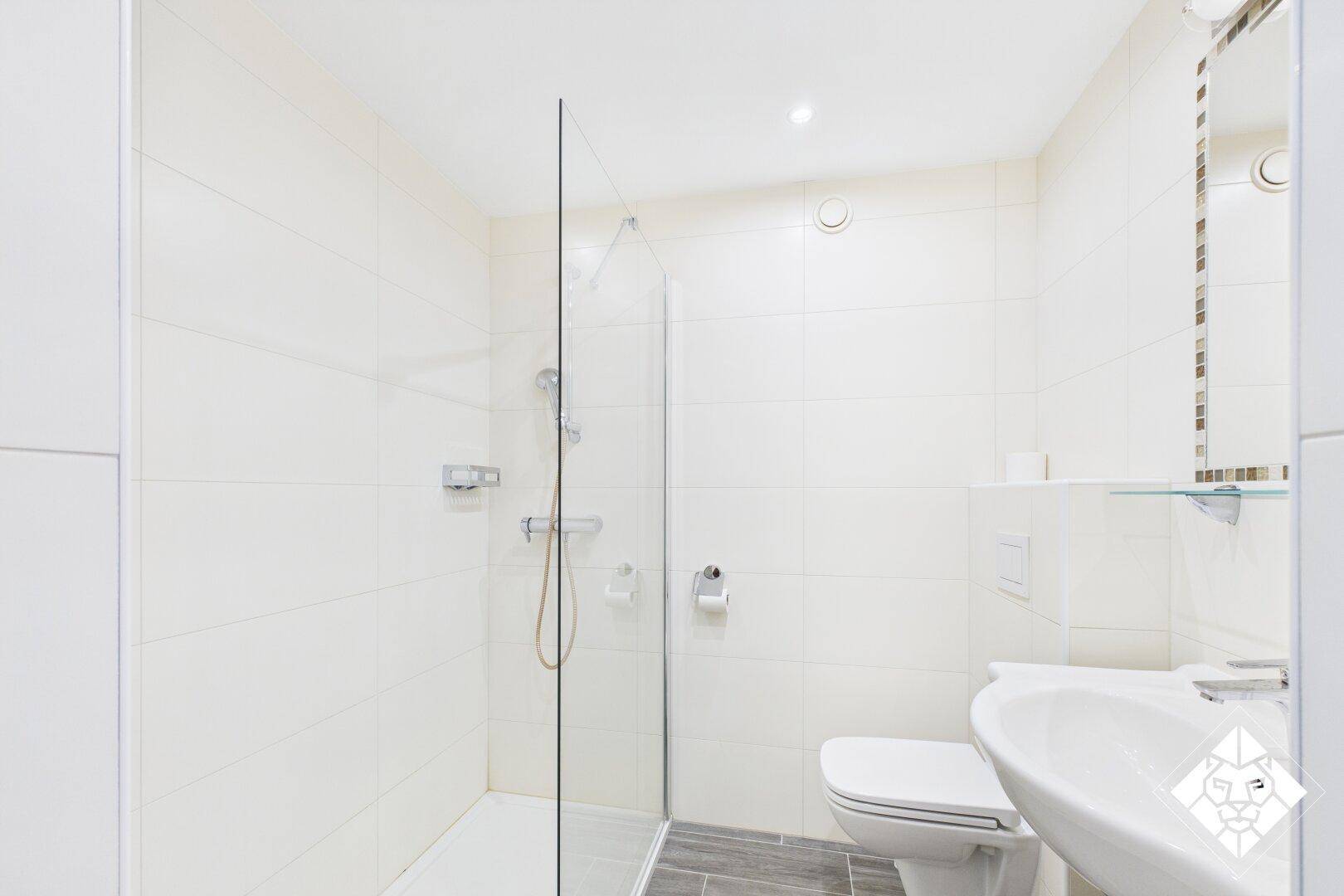 Modernes Badezimmer mit weißen Fliesen, ebenerdiger Dusche und einem einzelnen Waschbecken.