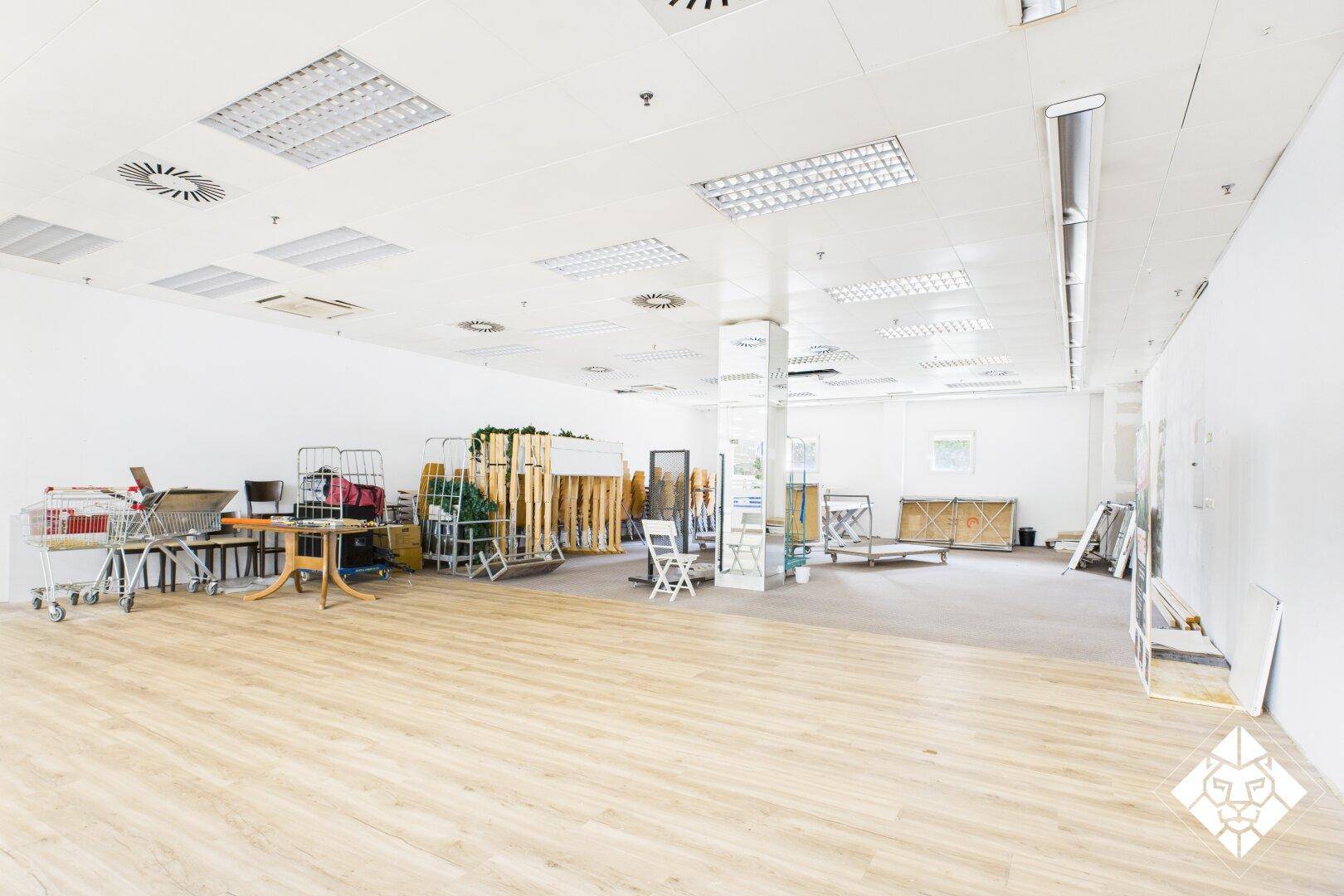 Geräumiger, leerstehender Gewerberaum mit Laminatboden und hoher Decke, bereit für individuelle Gestaltung.