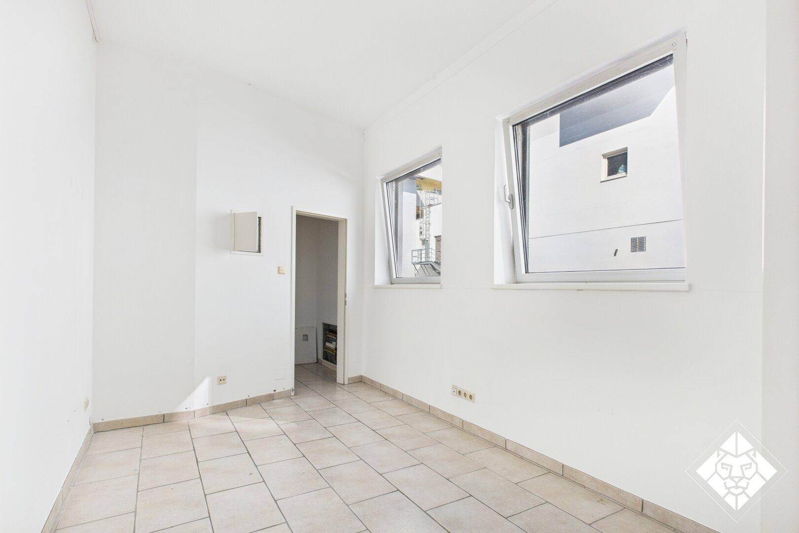 Kleiner, heller Raum mit zwei Fenstern und Fliesenboden, ideal als Büro oder Behandlungszimmer nutzbar.