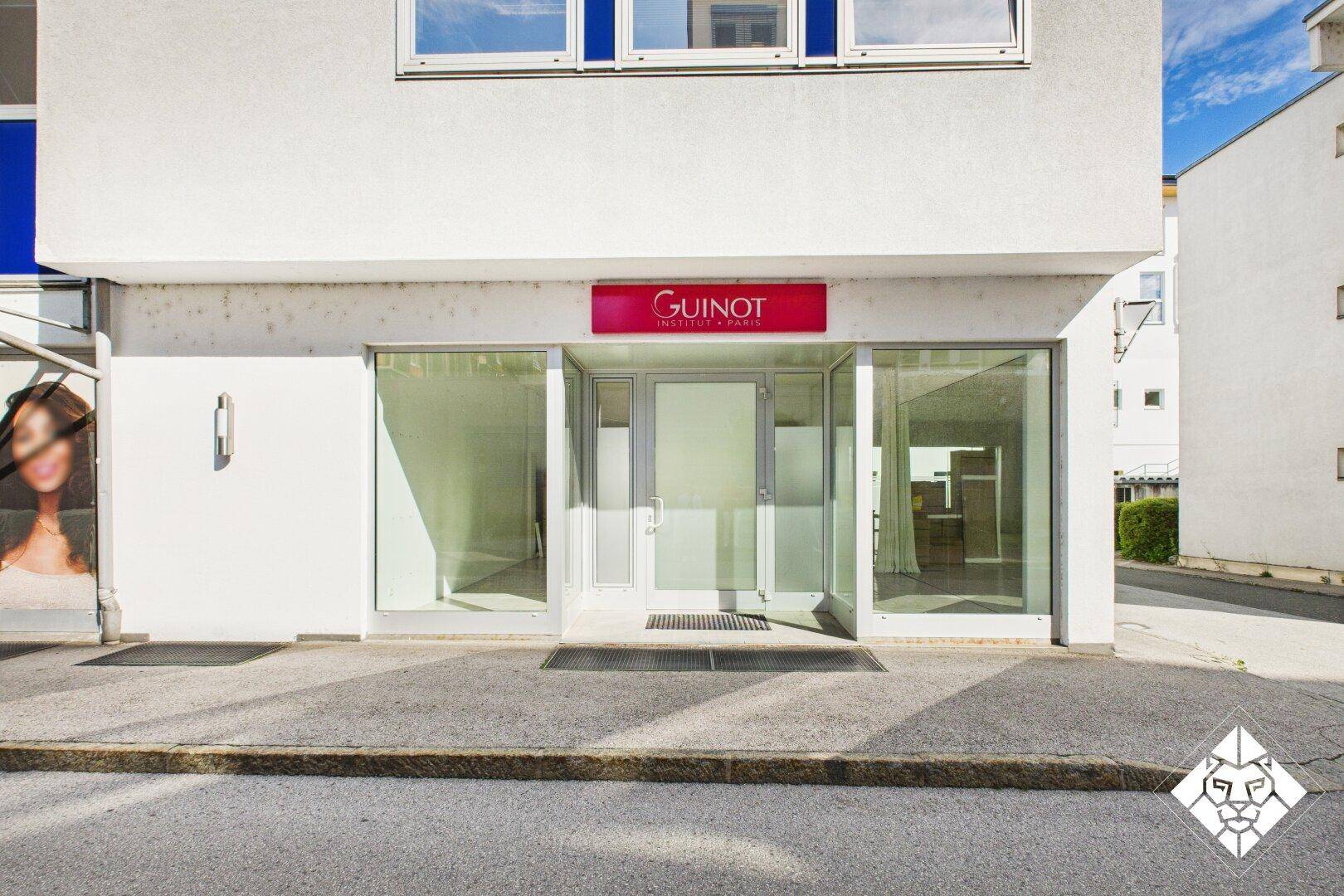 Fassade eines Geschäftsgebäudes mit großflächigen Glasfronten und dem Eingang zu einem Institut.