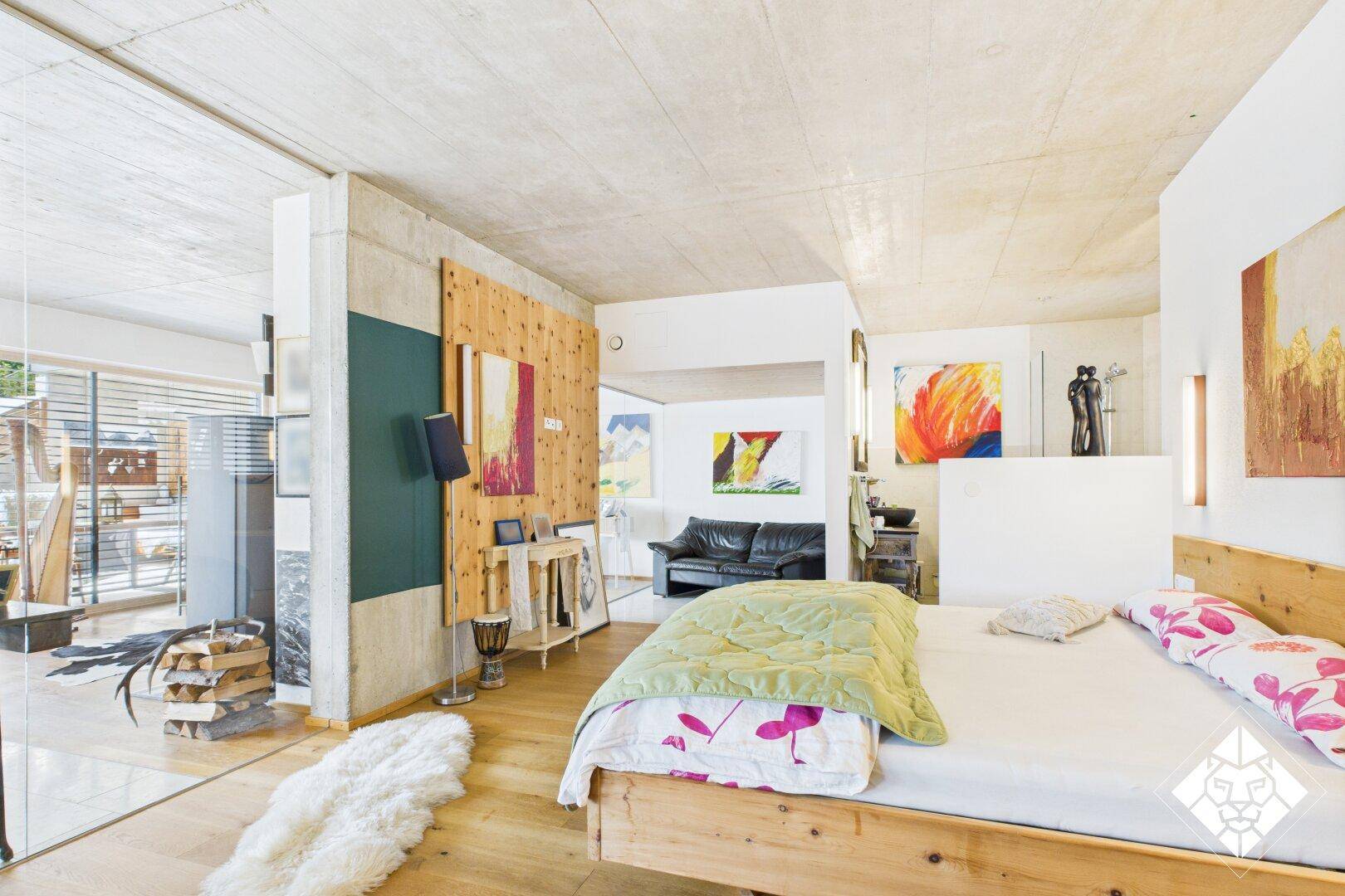 Helles Schlafzimmer mit Holzbett, Holzboden und großen Fenstern, offen zum Wohnbereich.