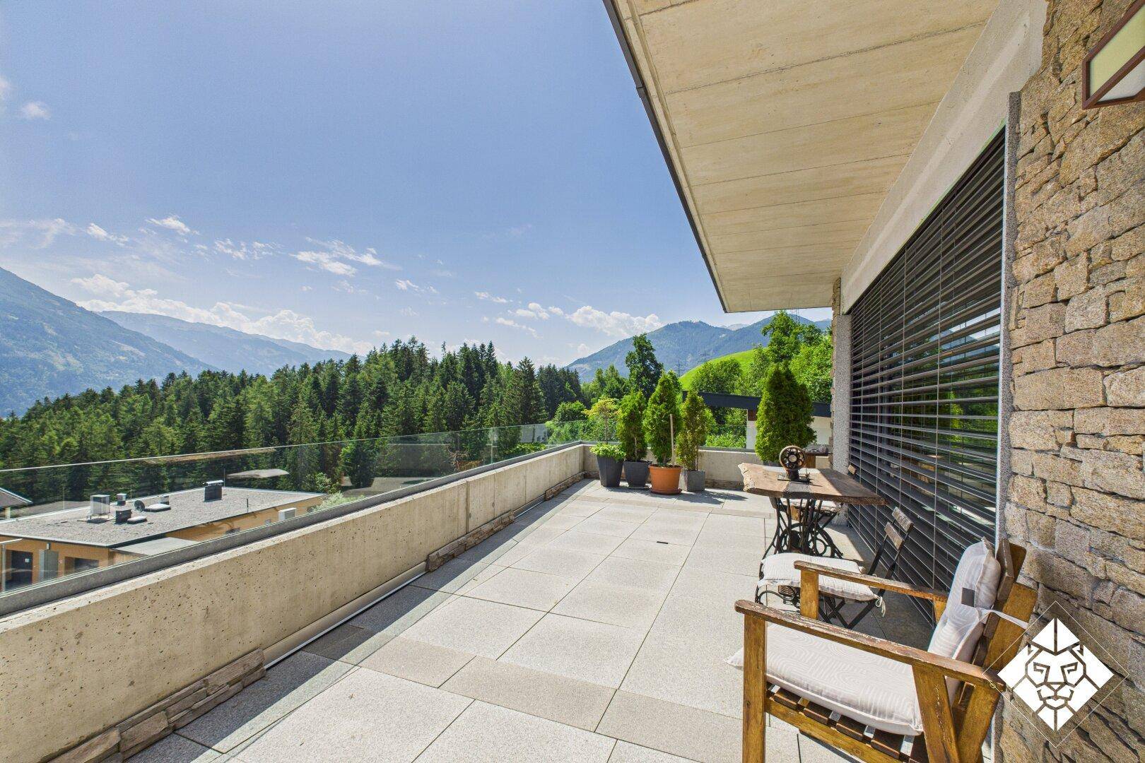 Weitläufige Terrasse mit Glasgeländer und atemberaubendem Panoramablick auf die Berge.