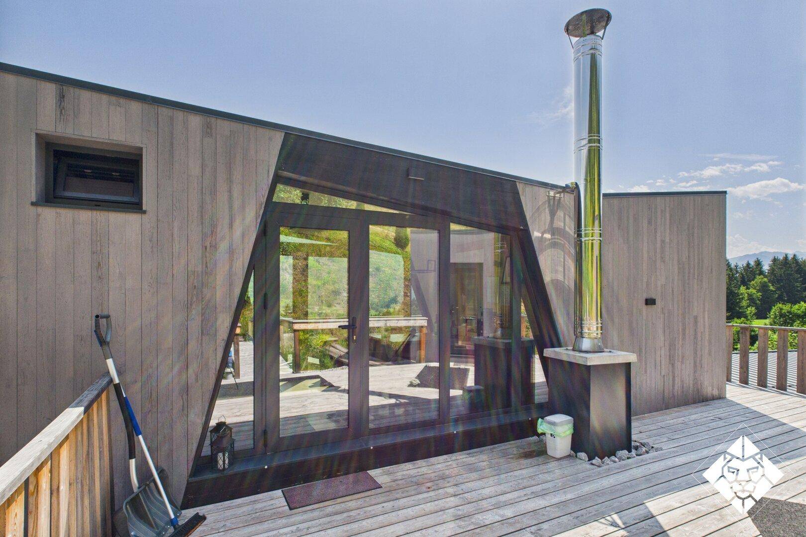 Moderne Holzfassade mit großen Glasfronten und einer Holzterrasse im Freien.