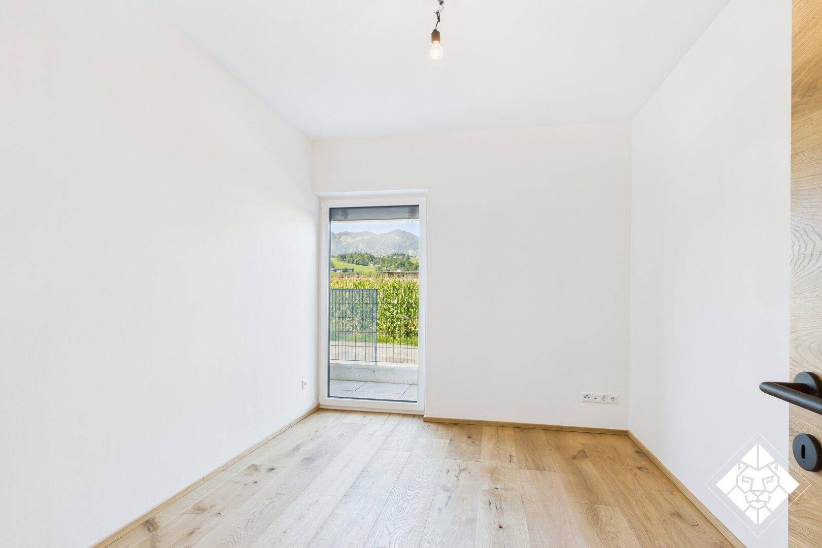 Helles Schlafzimmer mit Holzboden und Zugang zu einem kleinen Balkon mit schöner Aussicht.