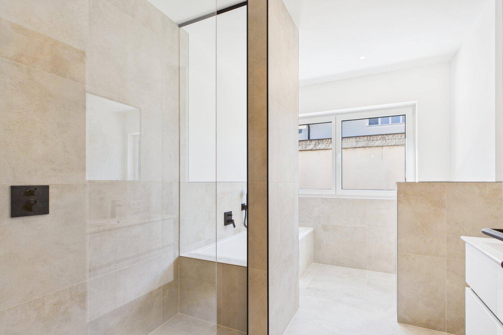 Modernes Badezimmer mit beigefarbenen Fliesen, Duschbereich und Badewanne.