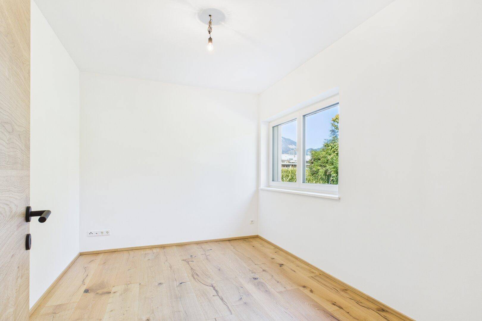 Ruhiges Schlafzimmer mit Holzboden und Fenster, das viel natürliches Licht bietet.