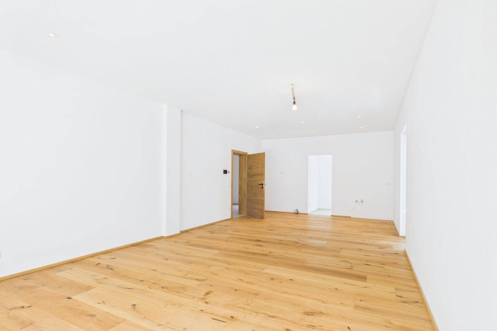 Lichtdurchfluteter Wohnraum mit Eichenparkett und minimalistischem Design, bereit zur individuellen Gestaltung.