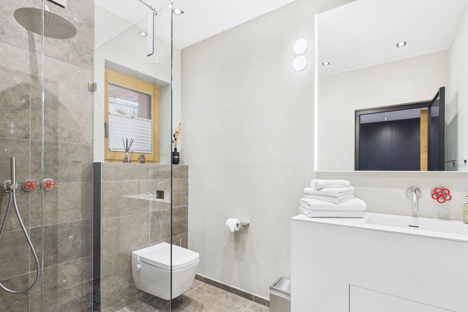 Modernes Badezimmer mit begehbarer Dusche, Wand-WC und Fenster für Tageslicht.