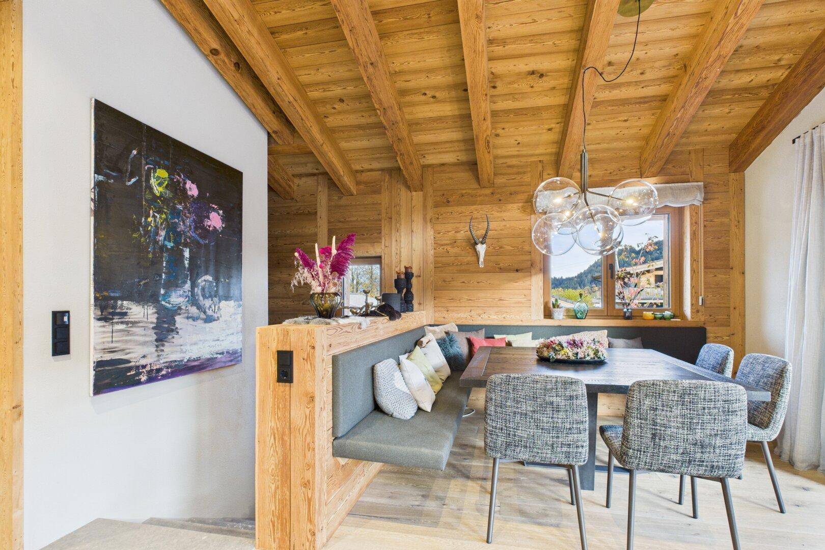 Gemütlicher Essbereich mit Holzwänden, integrierter Sitzbank und stilvoller Beleuchtung.