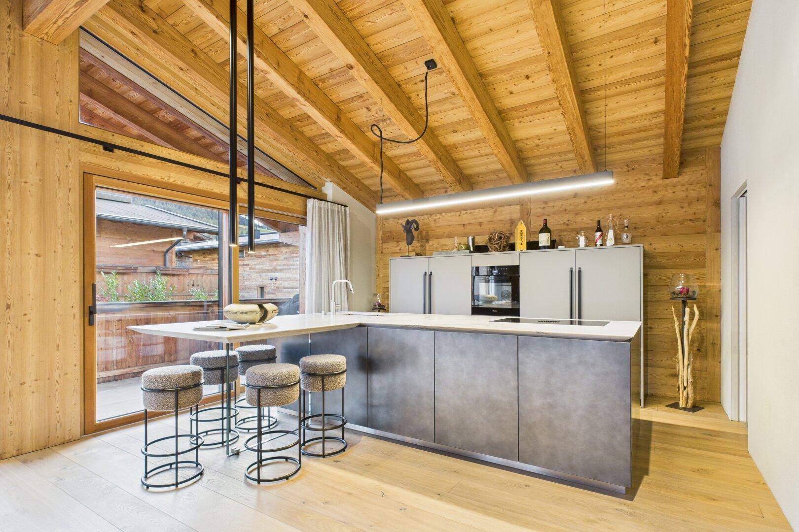 Moderne Küche mit Kochinsel, integrierten Geräten und rustikaler Holzbalkendecke.