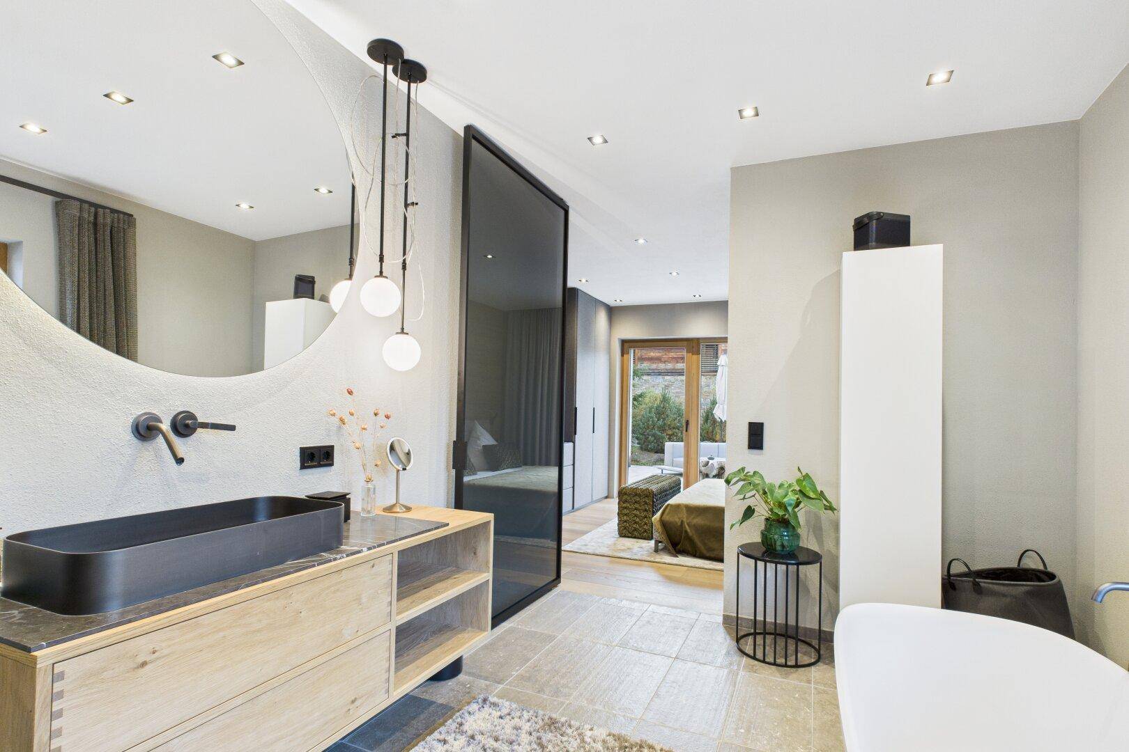 Elegantes Badezimmer mit modernem Waschtisch, großem Spiegel und Blick ins Schlafzimmer.