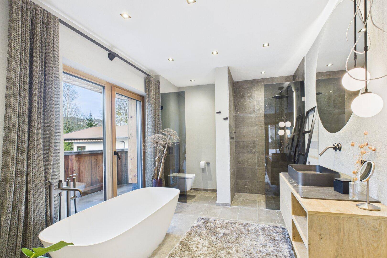 Luxuriöses Badezimmer mit freistehender Badewanne, Doppelwaschbecken und Balkonzugang.