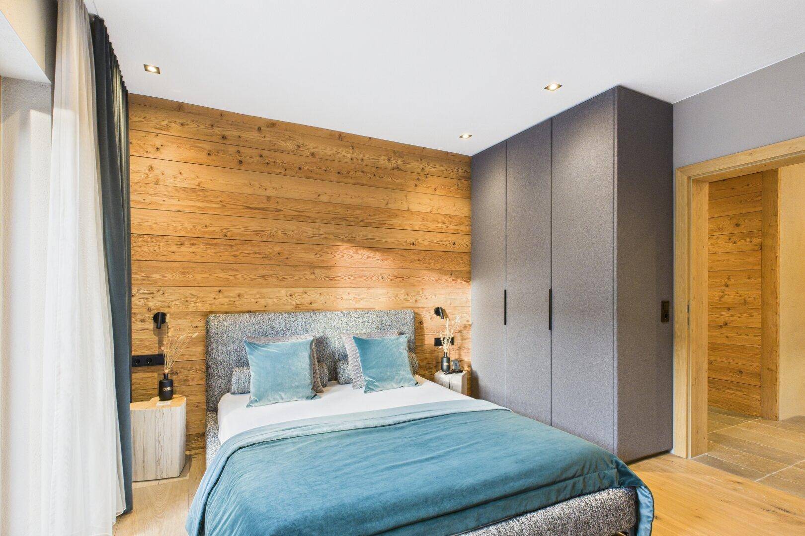 Modernes Schlafzimmer mit Holzwand, Einbauschränken und gemütlichem Doppelbett.