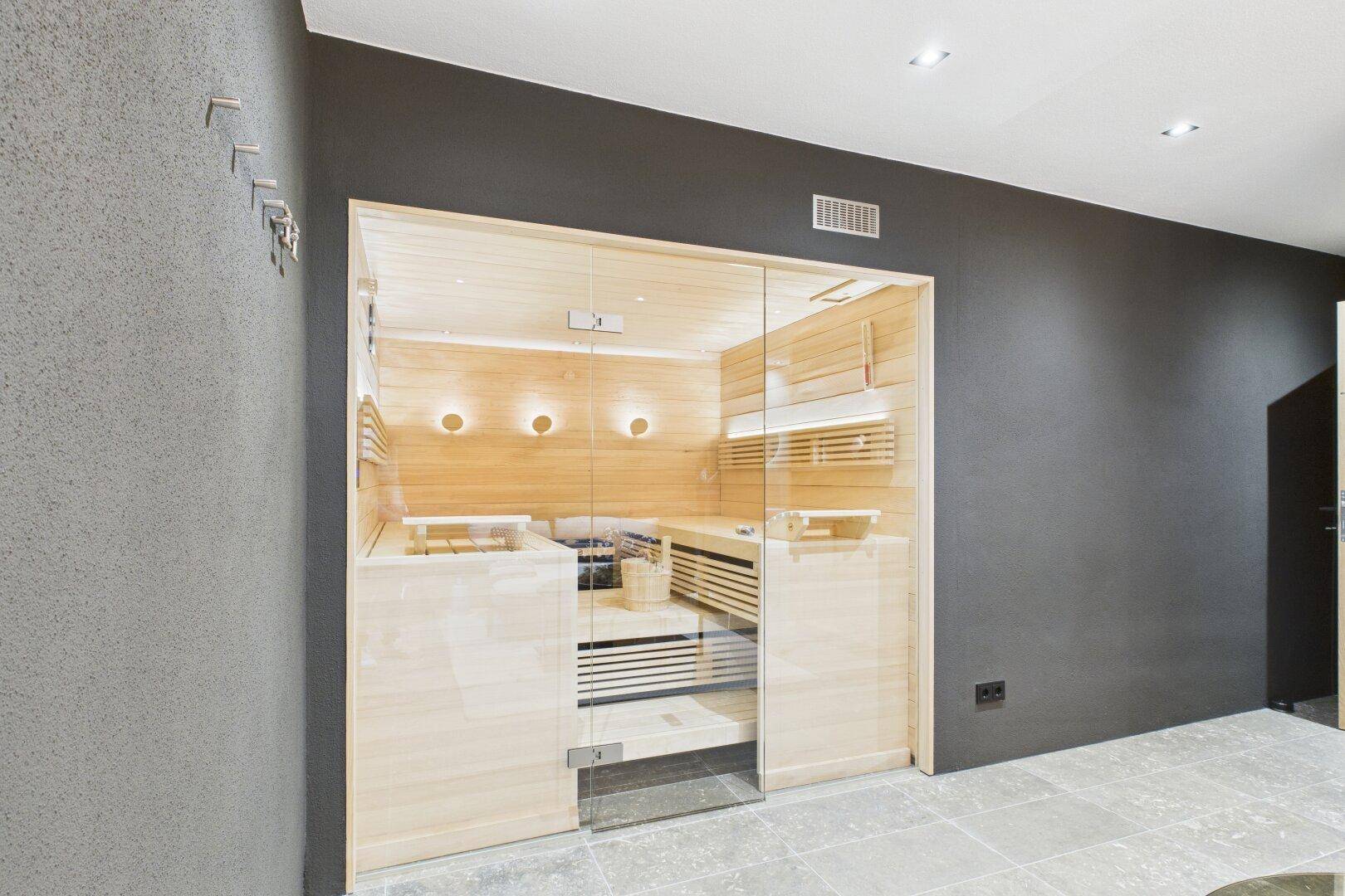 Moderne Sauna mit Holzbänken und Glasfront, ideal für Wellness und Entspannung.