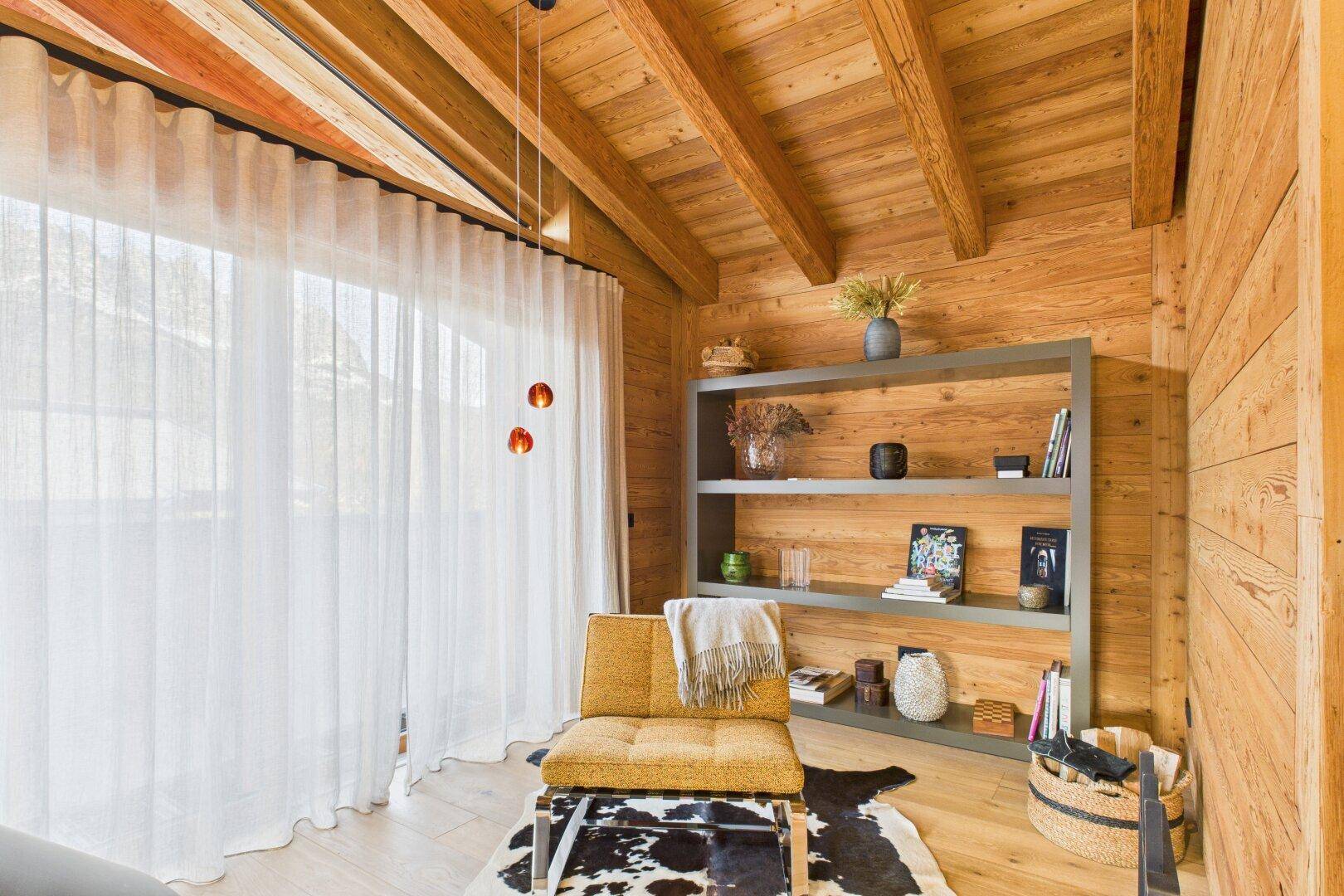 Heller Lesebereich mit großem Fenster, Bücherregal und stilvoller Einrichtung.