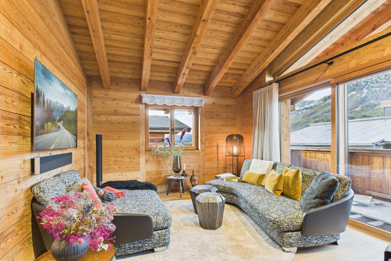 Gemütliches Wohnzimmer mit bequemer Couch, Holzwänden und Blick auf die Umgebung.