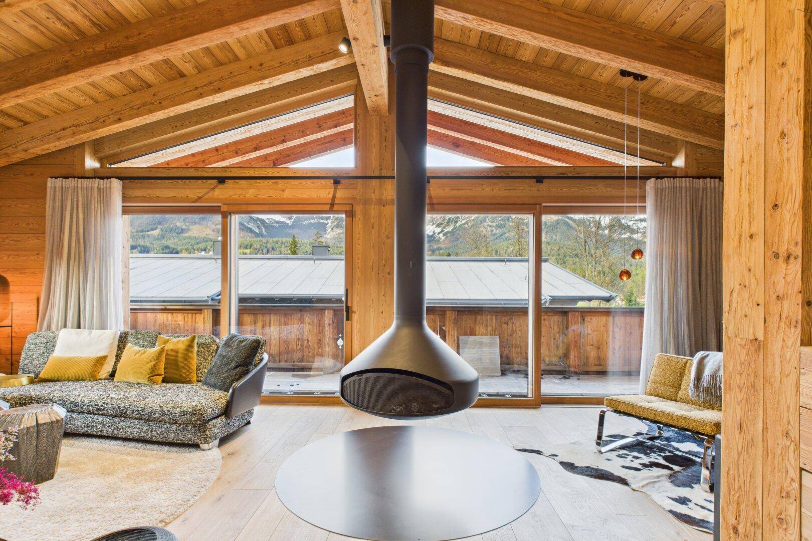 Elegantes Wohnzimmer mit schwebendem Kamin, hohen Decken und großen Fenstern mit Bergblick.