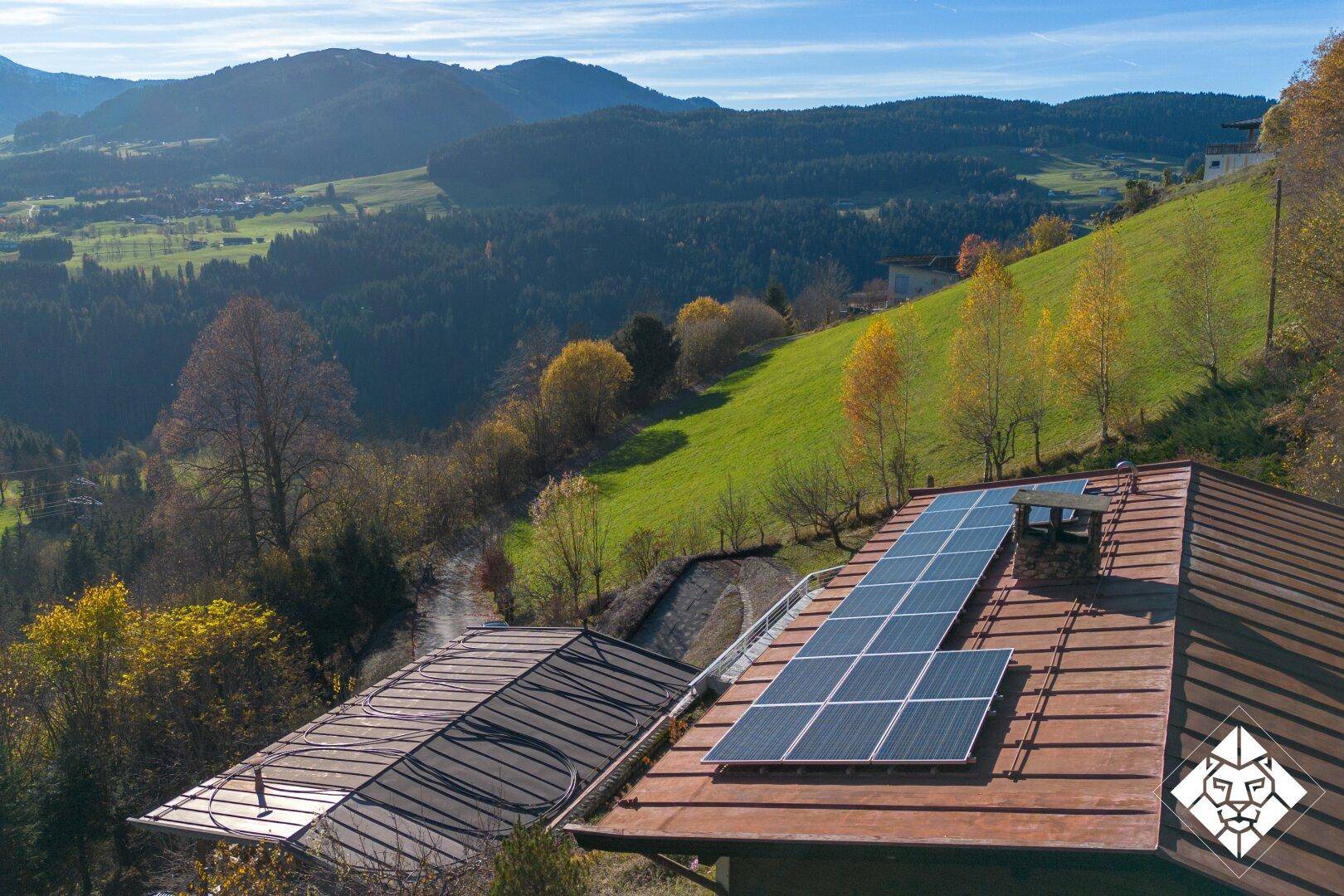 Dach des Haupthauses mit Photovoltaikanlage und weitem Blick über die alpine Landschaft.