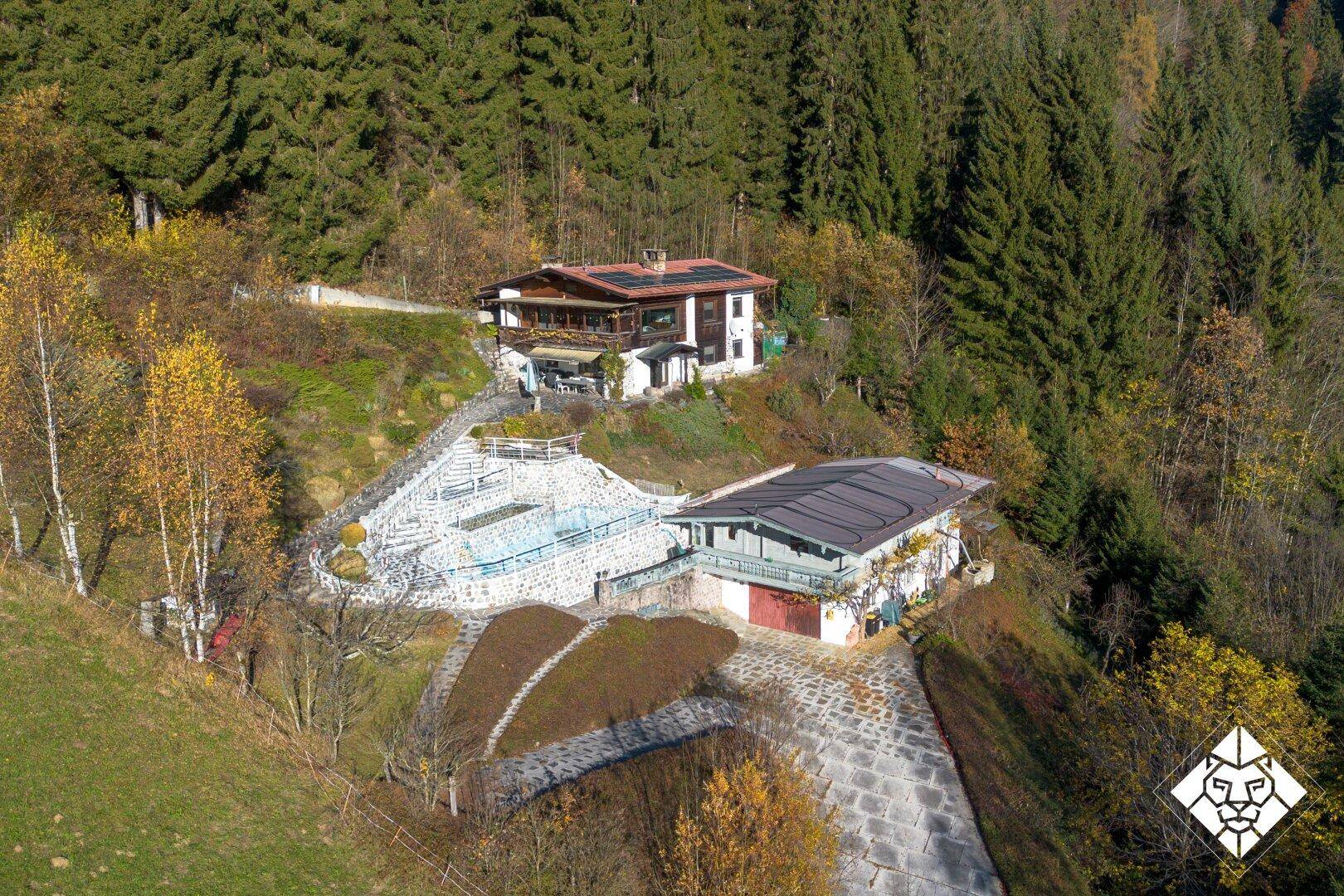 Luftaufnahme des Anwesens mit Haupthaus, Poolbereich und Nebengebäude in der herbstlichen Landschaft.