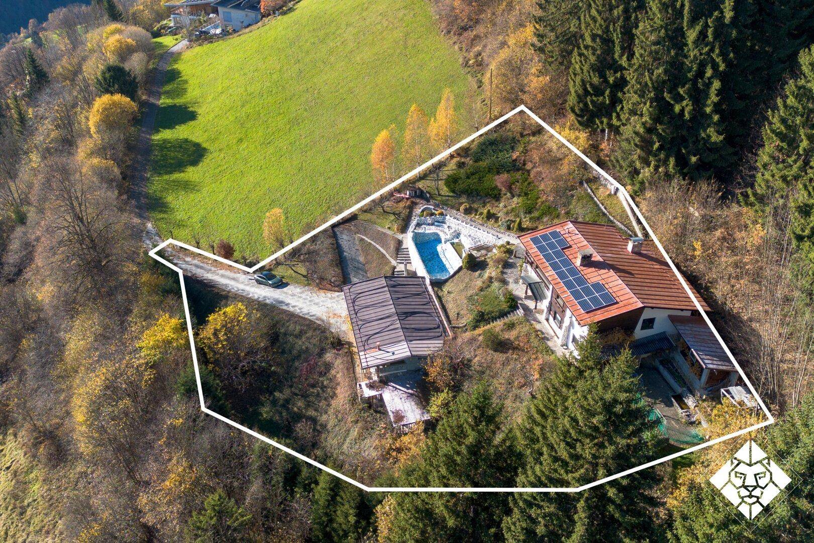 Luftaufnahme des Anwesens mit markierten Grundstücksgrenzen, Pool und umgebender Natur.
