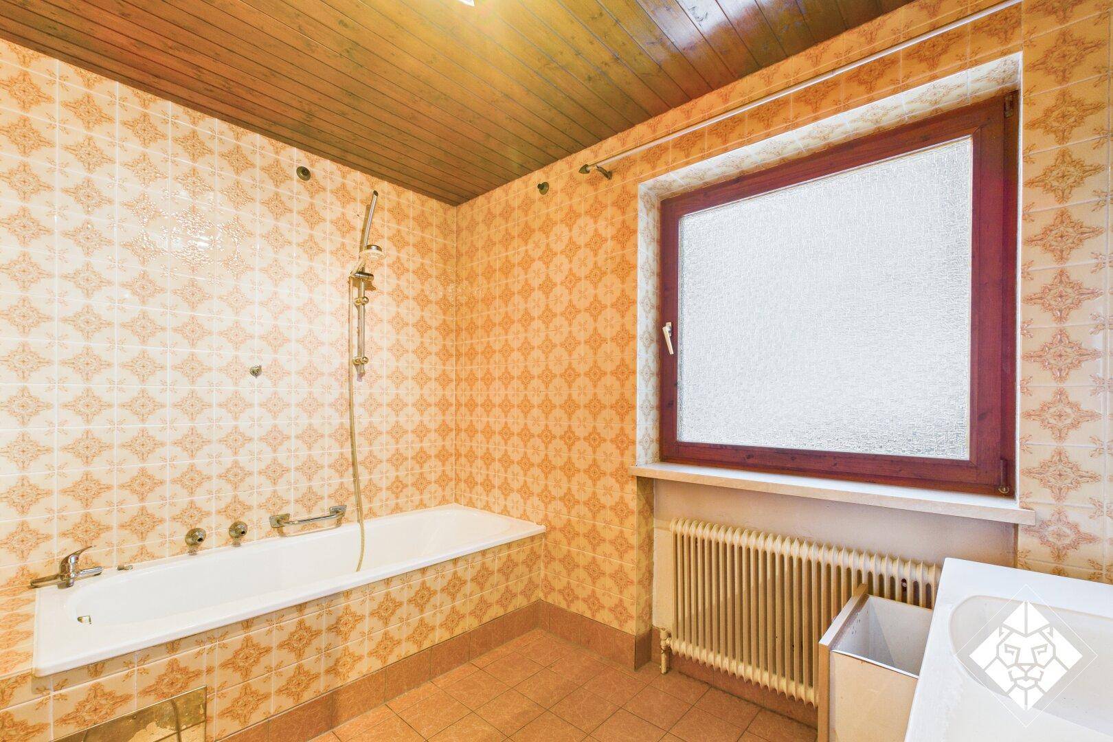 Badezimmer mit Badewanne, gemusterten Fliesen und Holzdecke in traditionellem Stil.
