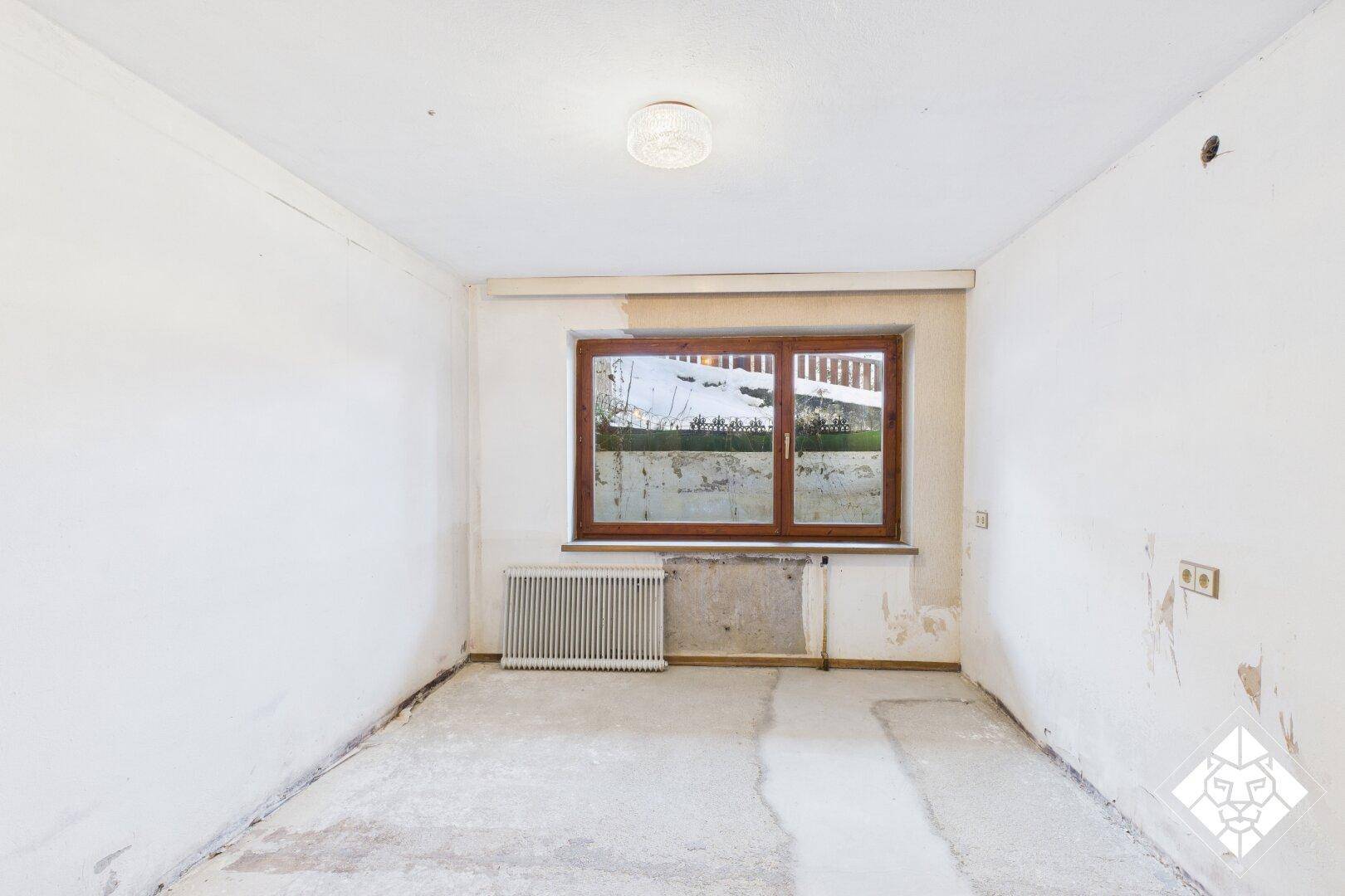 Einfacher Kellerraum mit Fenster und Heizkörper, bietet zusätzlichen Stauraum.