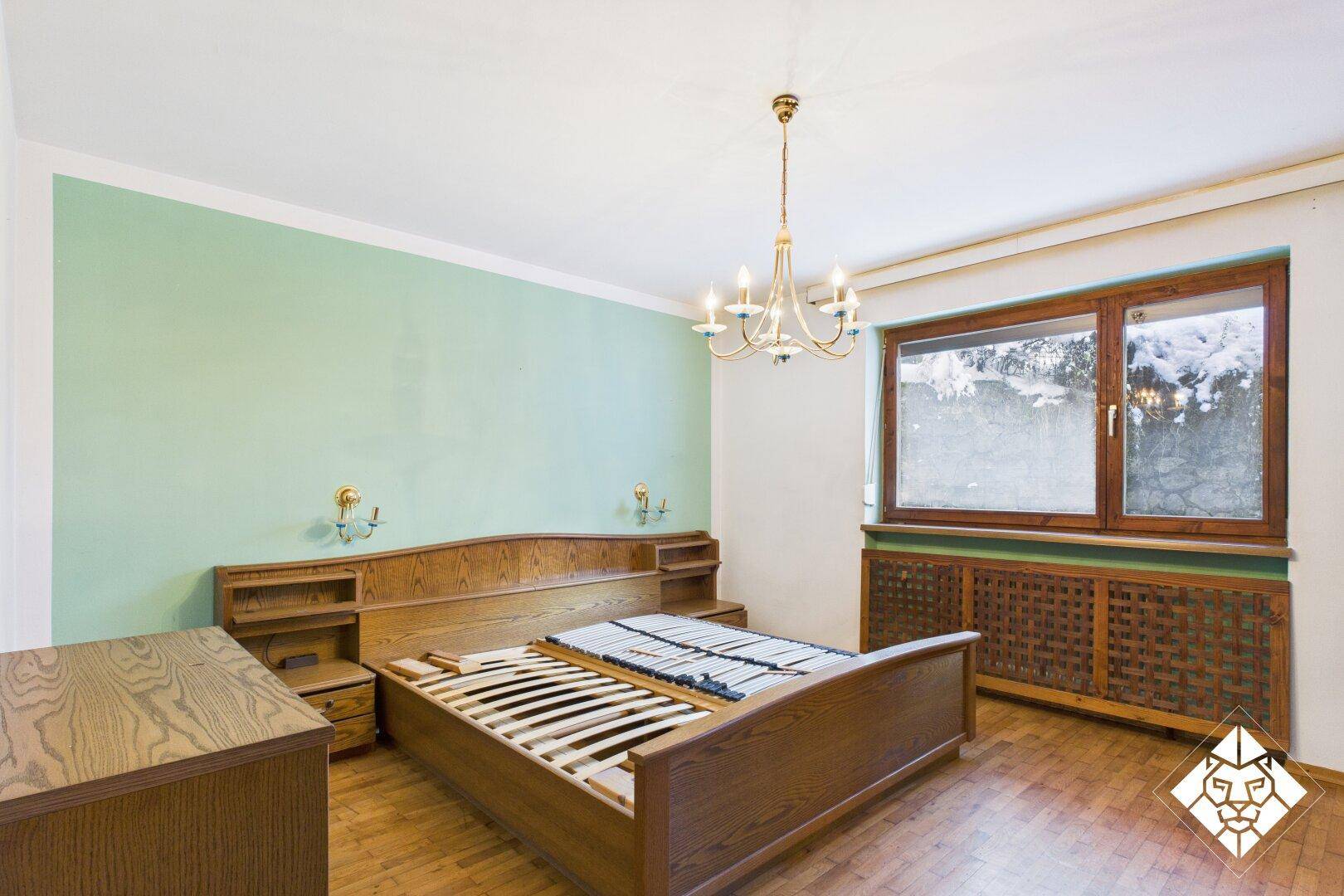 Schlafzimmer mit Holzbett, Parkettboden und hellgrüner Akzentwand in traditionellem Stil.